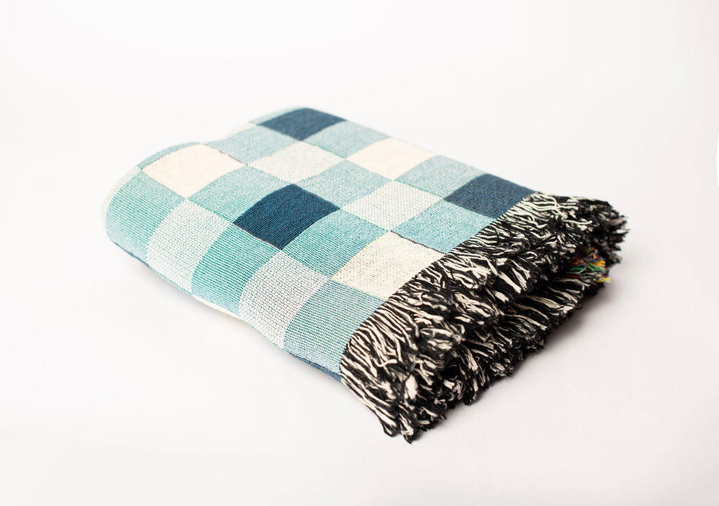 Folded Tilda Bayberry blue check woven cotton throw blanket with black and cream fringe