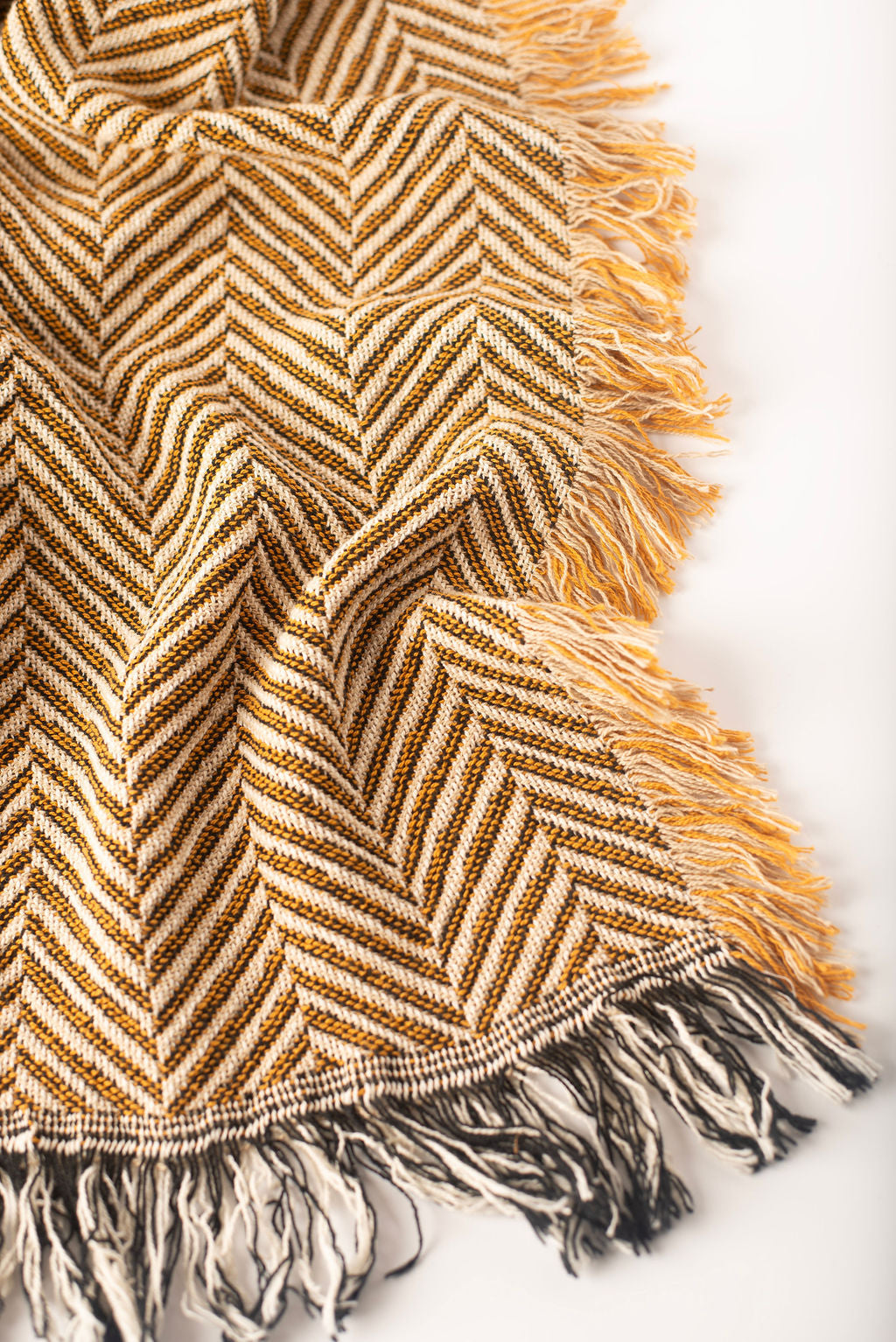 Henry Verbena green herringbone woven cotton throw blanket draped over a neutral sofa