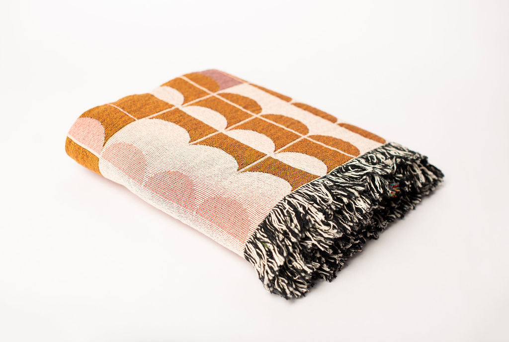 Folded Quinn Blush pink scallop jacquard woven throw blanket with black and cream fringe