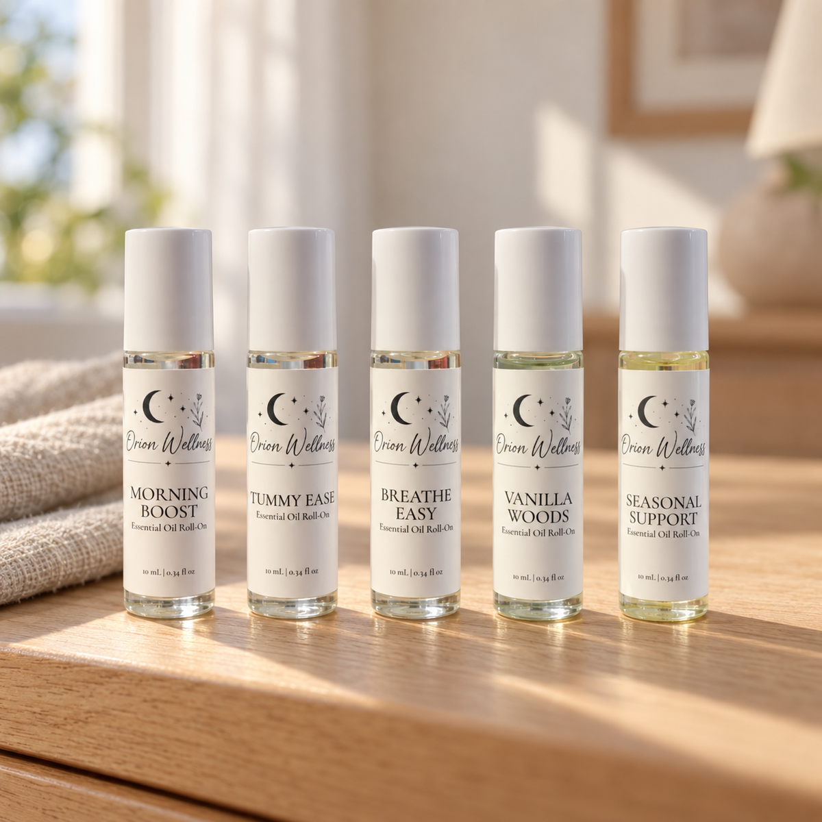 Orion Wellness five-piece set: Morning Boost, Tummy Ease, Breathe Easy, Vanilla Woods, and Seasonal Support in a natural home setting