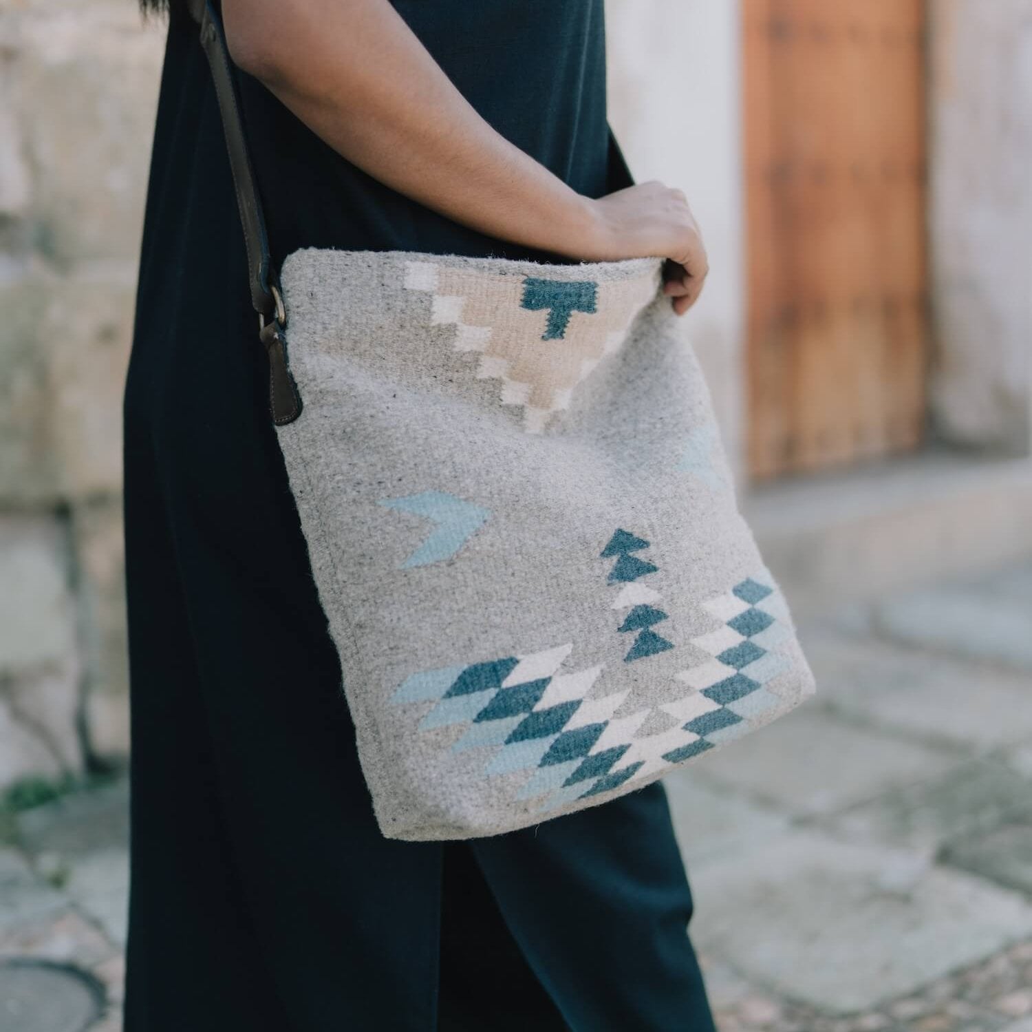 AMASOUK handwoven wool Aguila Shoulder/Crossbody bag featuring a Zapotec pattern in blue, ivory, and honey on a gray backdrop. Stylish and versatile for daily use and evening outings.