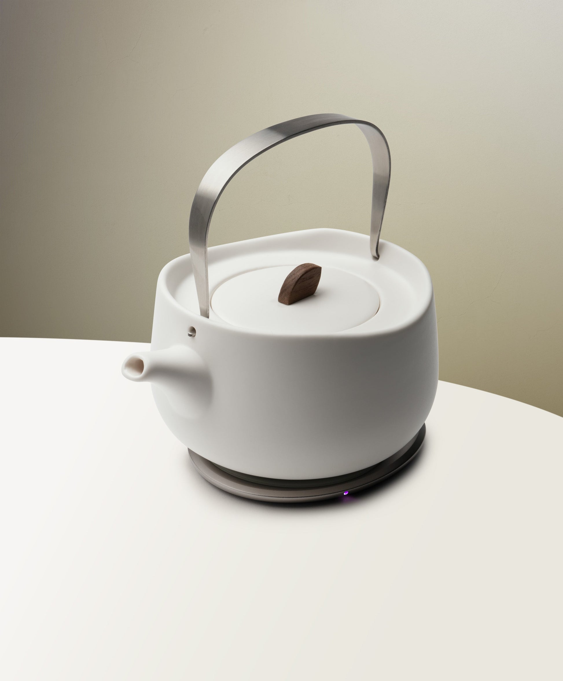 Leiph self-heating ceramic teapot 20 fl oz / 600 mL in Jasmine White charging on OHOM Pad 3, top side angle view