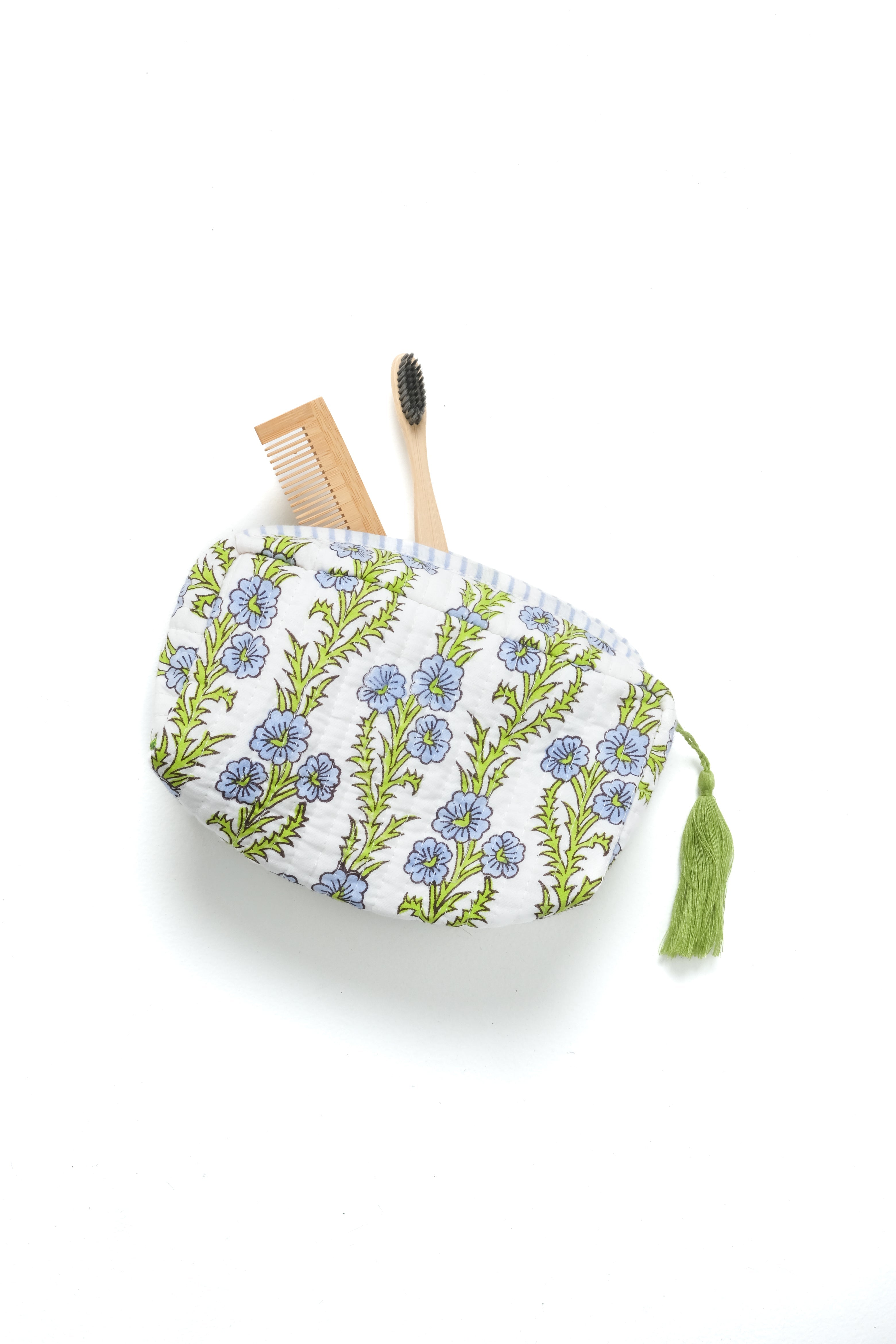 Blue blockprint makeup bag with forget-me-not floral pattern, green tassel, holding bamboo accessories