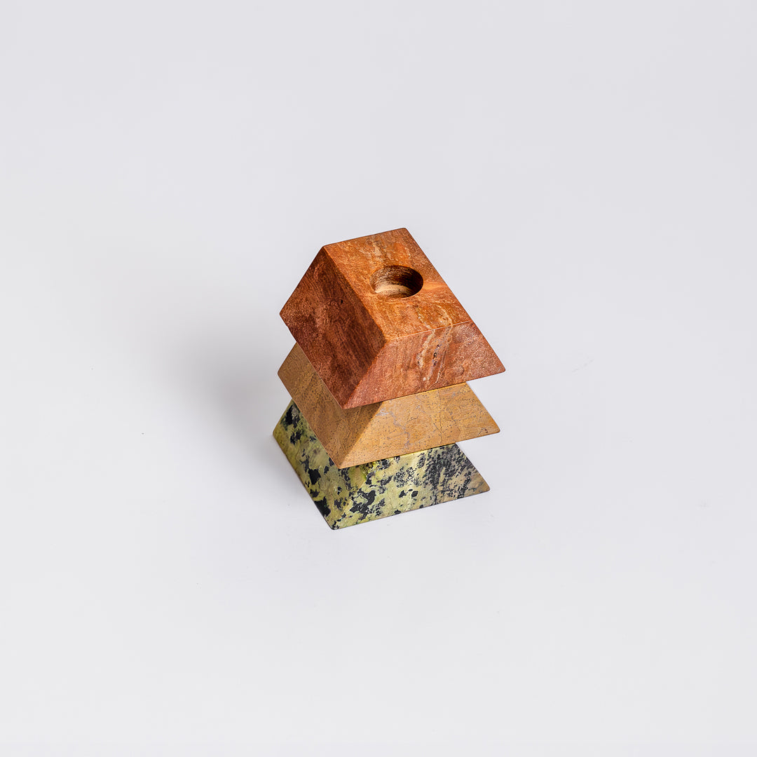 The solid green, orange, and cream stone candelabra partially separated, inviting tactile interaction and showcasing its sculptural depth.