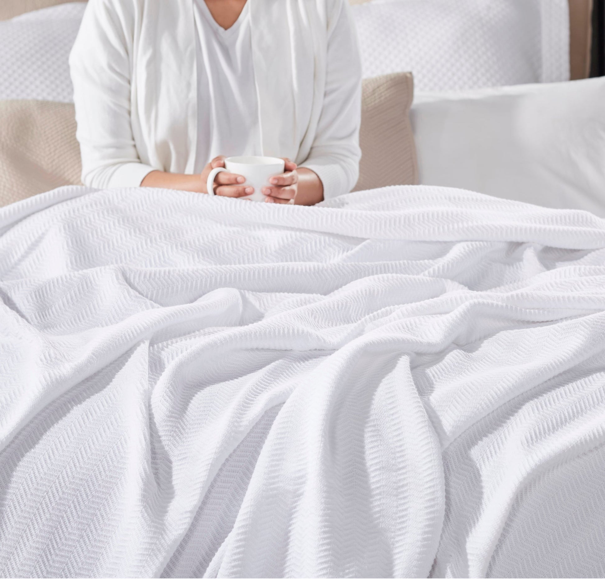 BL-853-9496_2|Person relaxing in bed with a mug, covered by a soft white waffle weave blanket, perfect for cozy morning comfort.