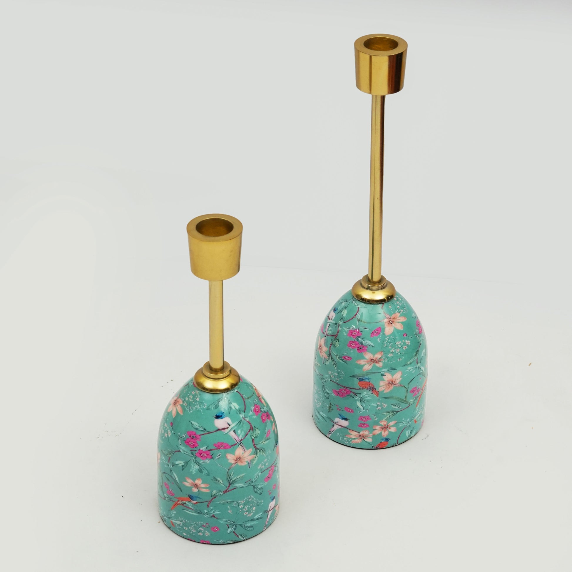 Two decorative candle holders with floral patterns and gold accents on a white background
