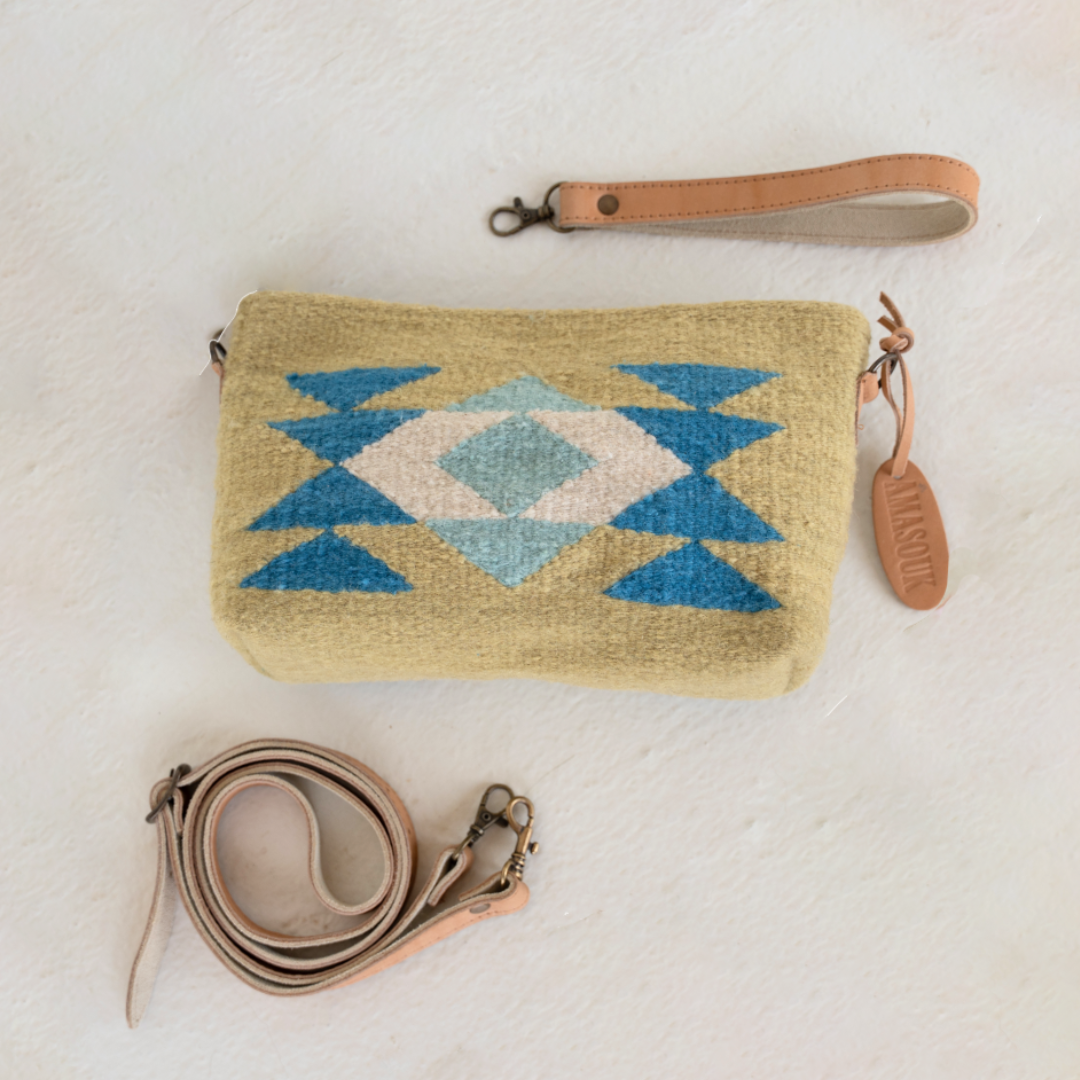 Woman wearing the handwoven convertible clutch with Zapotec butterfly design in bright spring colors; can be used as a pouch, wristlet, or crossbody with included leather straps and internal pocket