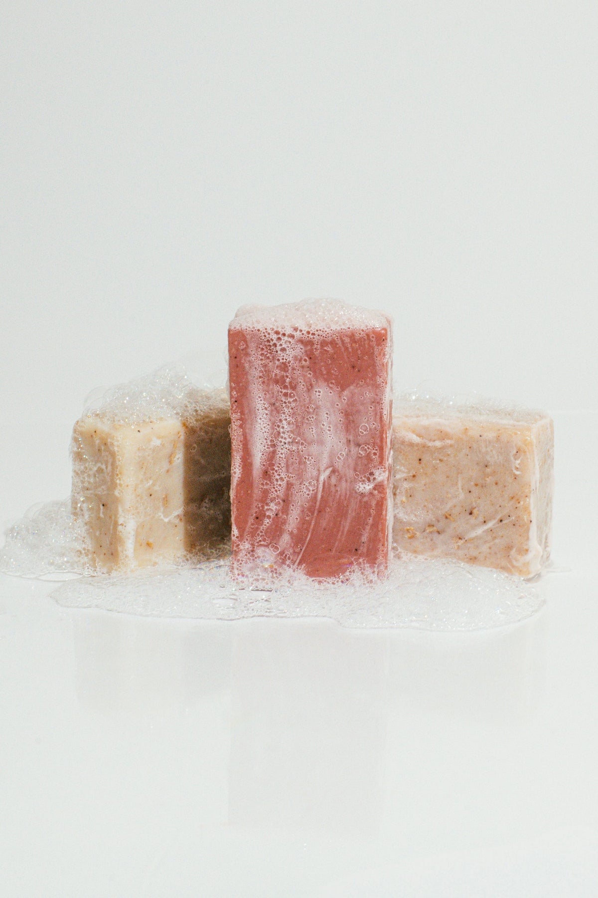 Wenjulan Whole Body Care Cleansing Bar Trio bundle gift pack featuring Wenjulan Unscented Cleansing Soap with Colloidal Oatmeal bar, Wenjulan Sensitive Skin Cleansing Soap with Kaolin Clay bar, Wenjulan Southwest Cedar Cleansing Soap bar with suds and lather on a light gray background