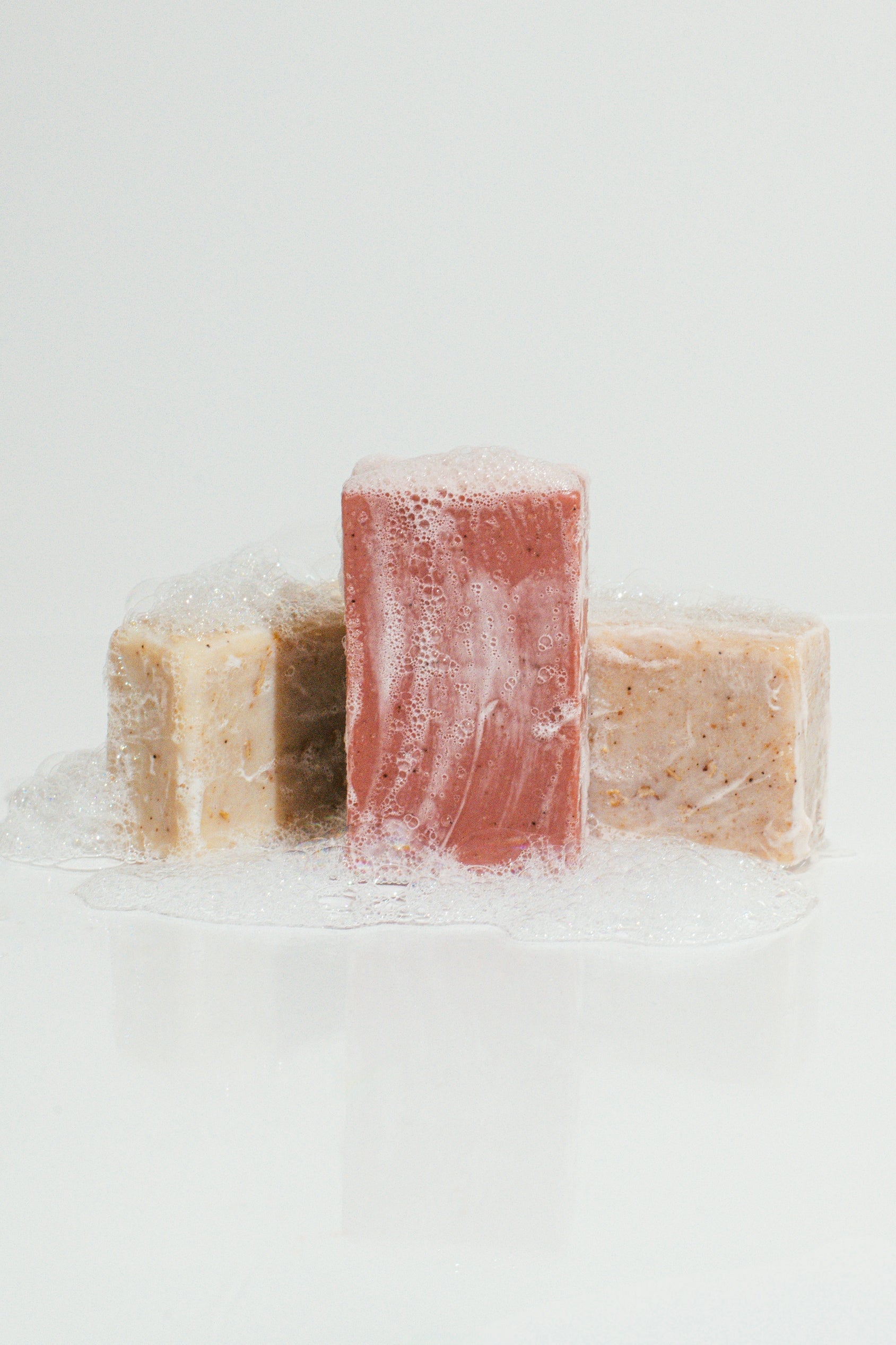 Wenjulan Whole Body Care Cleansing Bar Trio bundle gift pack featuring Wenjulan Unscented Cleansing Soap with Colloidal Oatmeal bar, Wenjulan Sensitive Skin Cleansing Soap with Kaolin Clay bar, Wenjulan Southwest Cedar Cleansing Soap bar with suds and lather on a light gray background