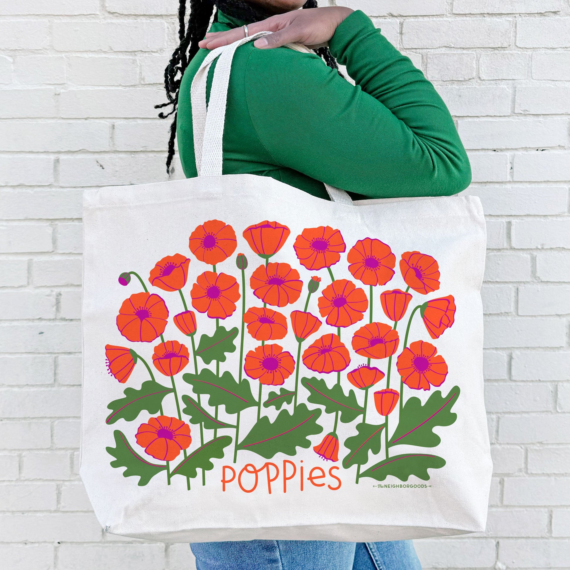 A woman carries the Poppies tote bag over her shoulder.