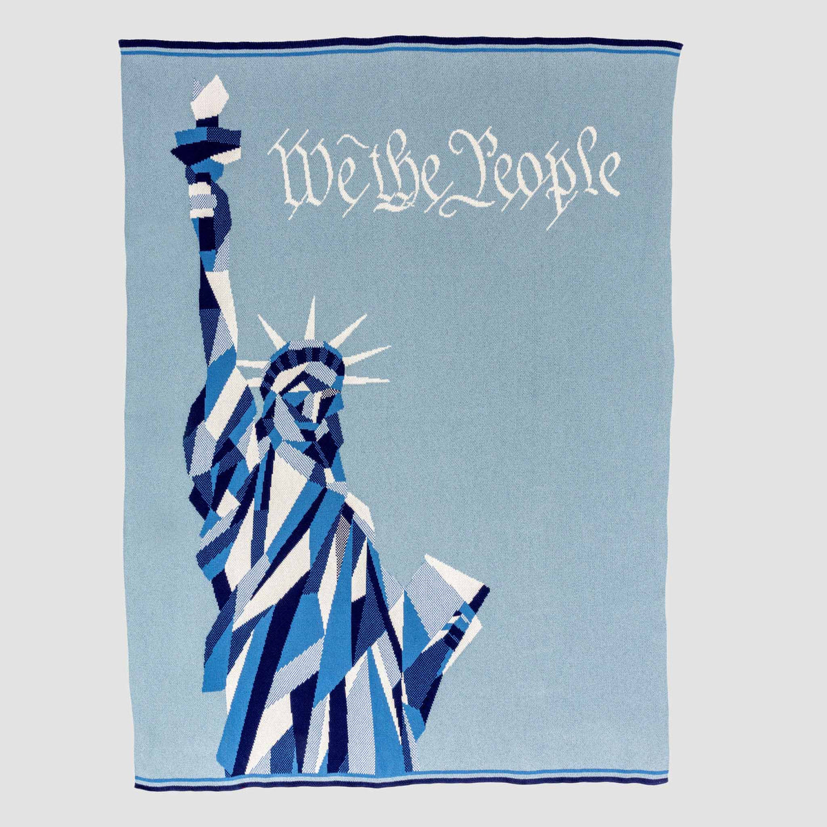 Wrap yourself in American identity with the in2green “Statue of Liberty | We the People” Cotton Sustainable Knit Modern Throw Blanket, featuring a blue and white geometric illustration of the Statue of Liberty and elegant script on a light blue background—a striking heritage accent for your home decor.