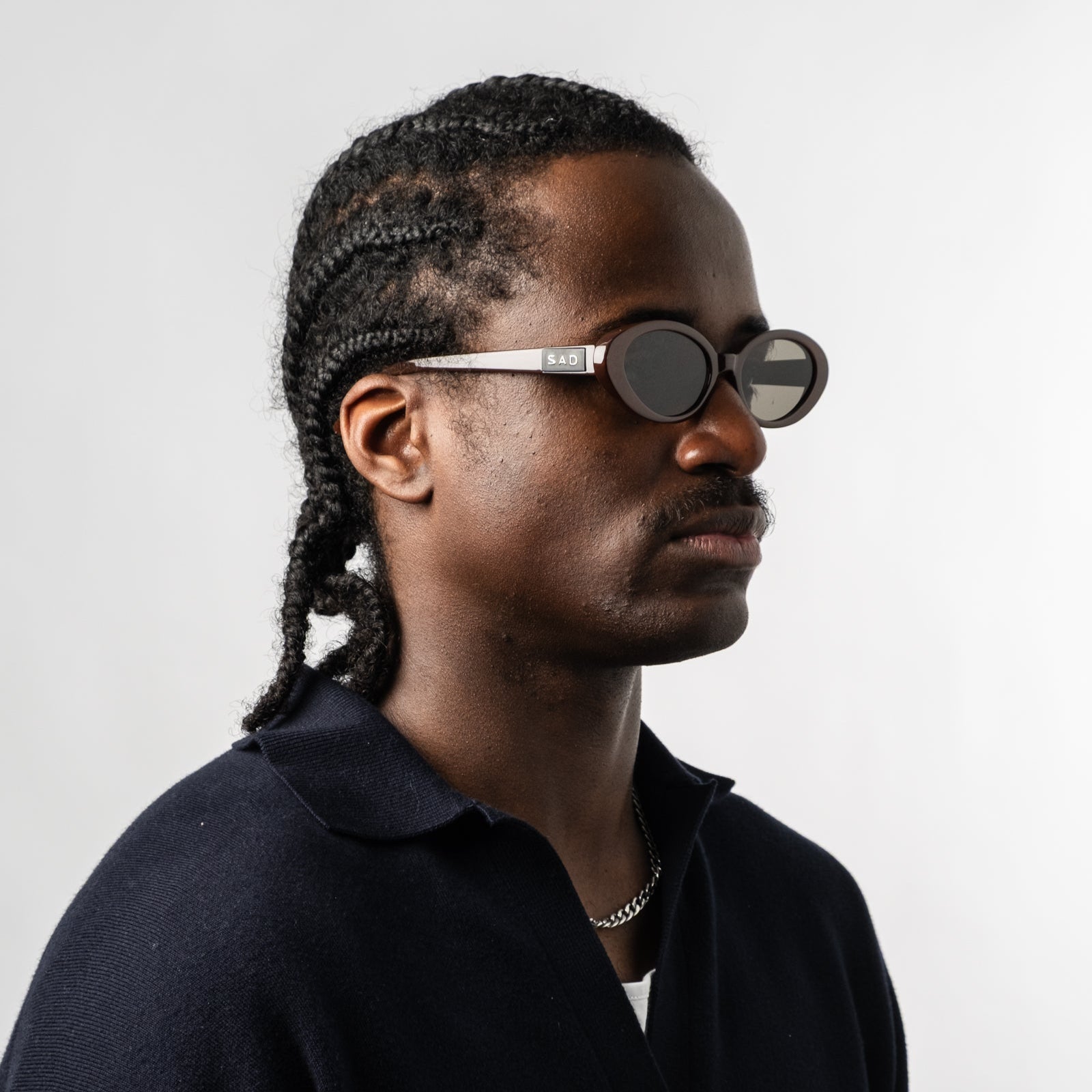 Male wearing Sad Eyewear Bloom oval sunglasses in tobacco red with tinted black lenses