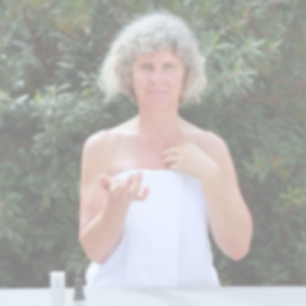 Video of woman outdoors applying Annmarie Herbal Facial Oil for Sensitive Skin while wrapped in a white towel in a natural garden setting.