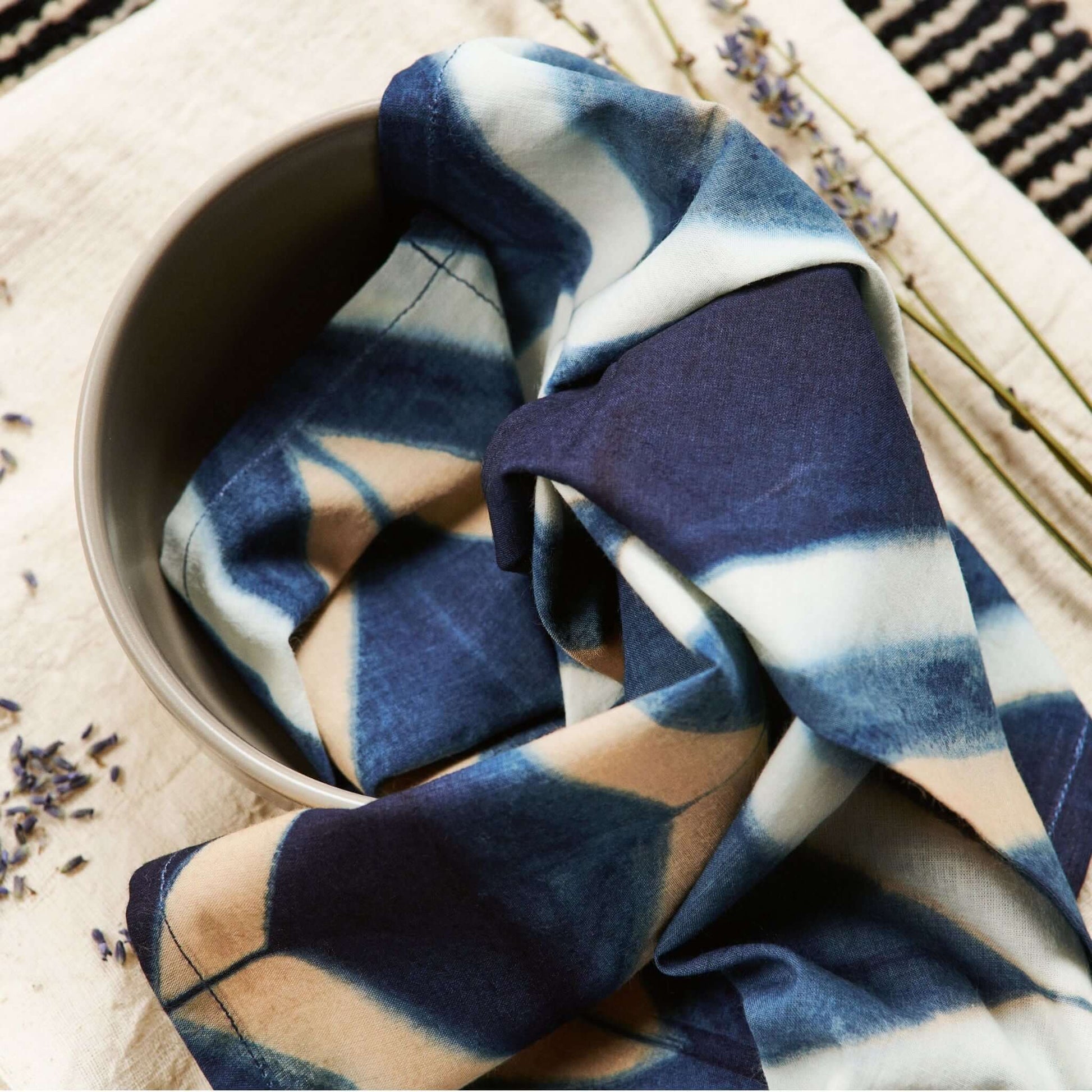 Tisa Indigo Hand Crafted Shibori Print Cotton Table Napkin set of 4 folded in a bowl, showcasing artistic dye pattern.