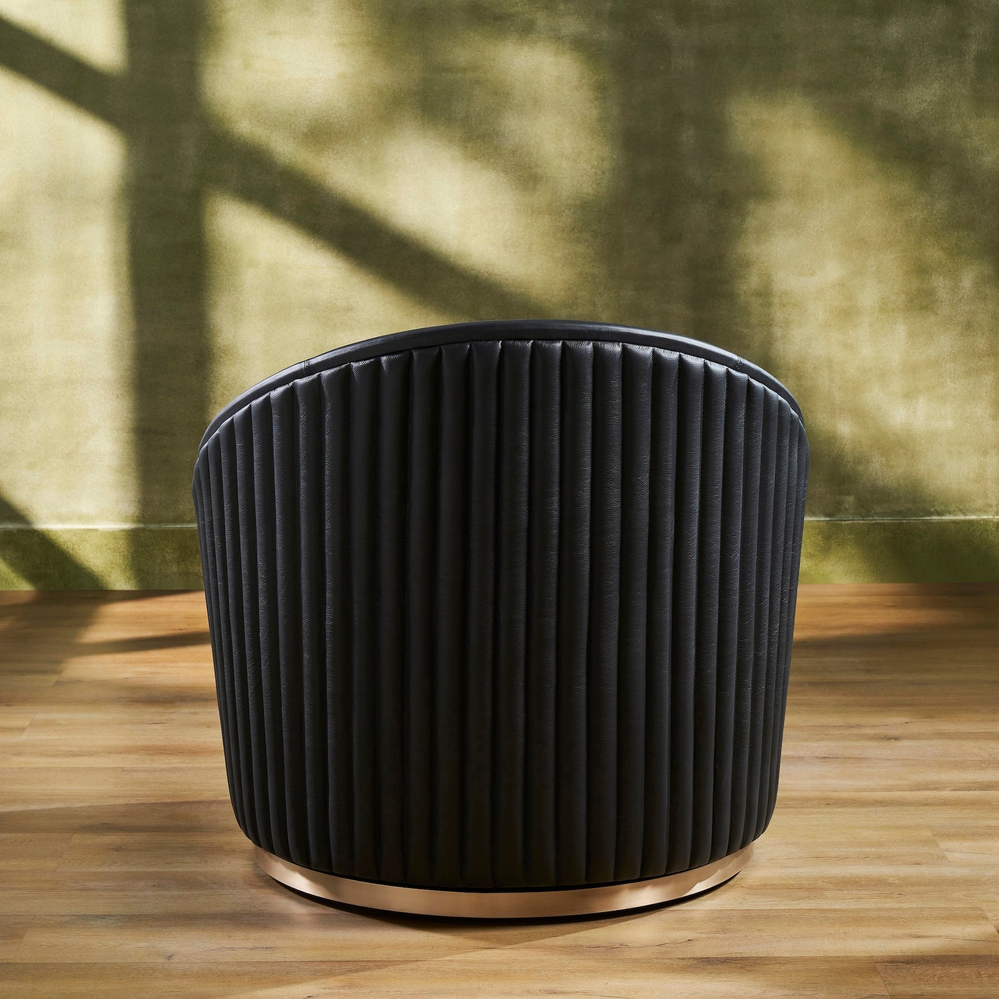 FN-5207-353529_4|Rear view of a sleek black leather swivel armchair, featuring striking vertical ribbed back detailing and a polished gold base.