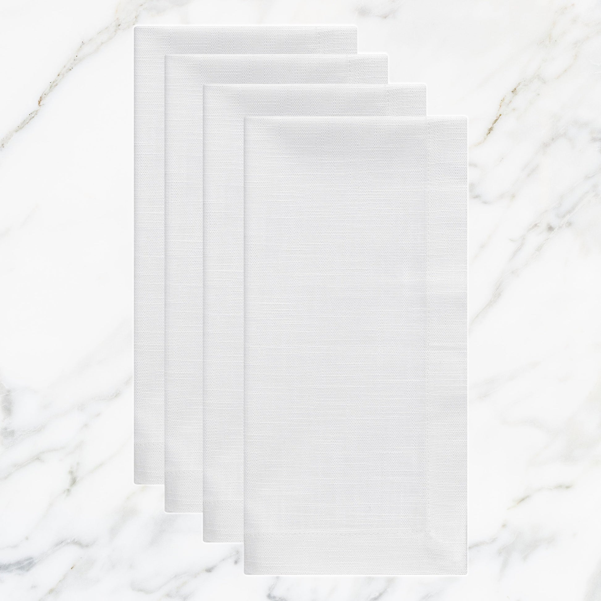 NP-4809-2020_1|Set of four crisp white linen-look fabric dinner napkins, folded on a sophisticated white marble surface.