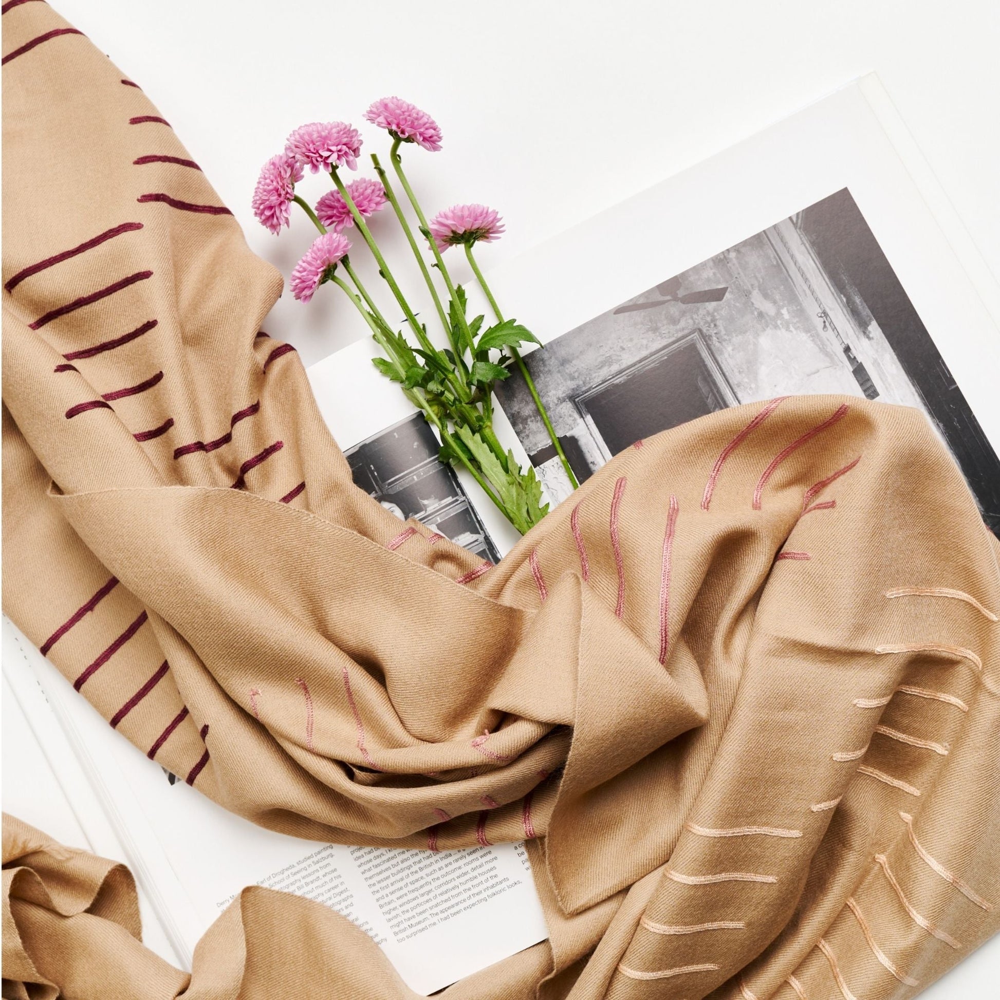 Maple Beige Handwoven Hand Embroidered Classic Scarf displayed with pink flowers on a book.