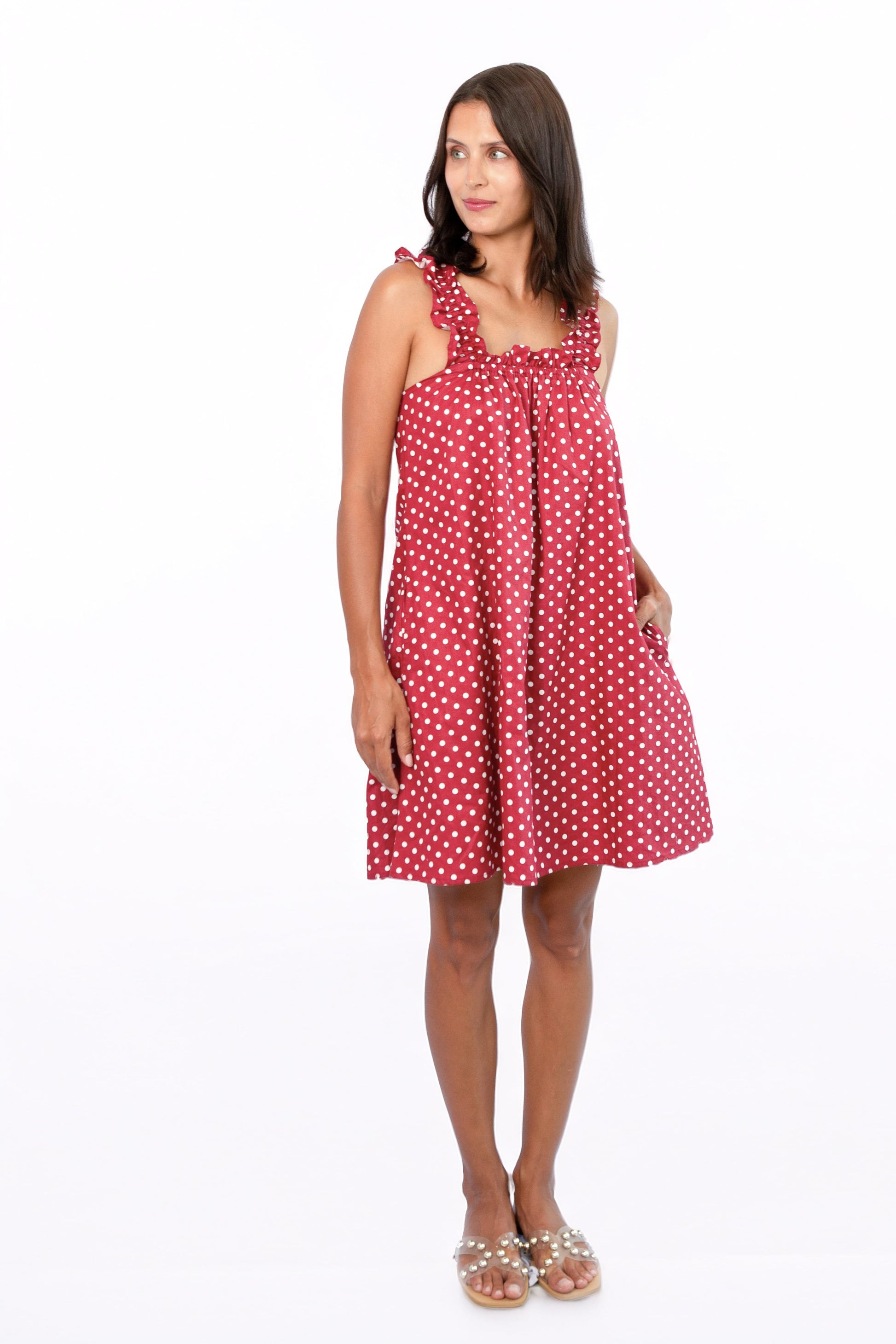 Mila Red — women's red and white polka dot cotton mini dress on a sun-lit balcony