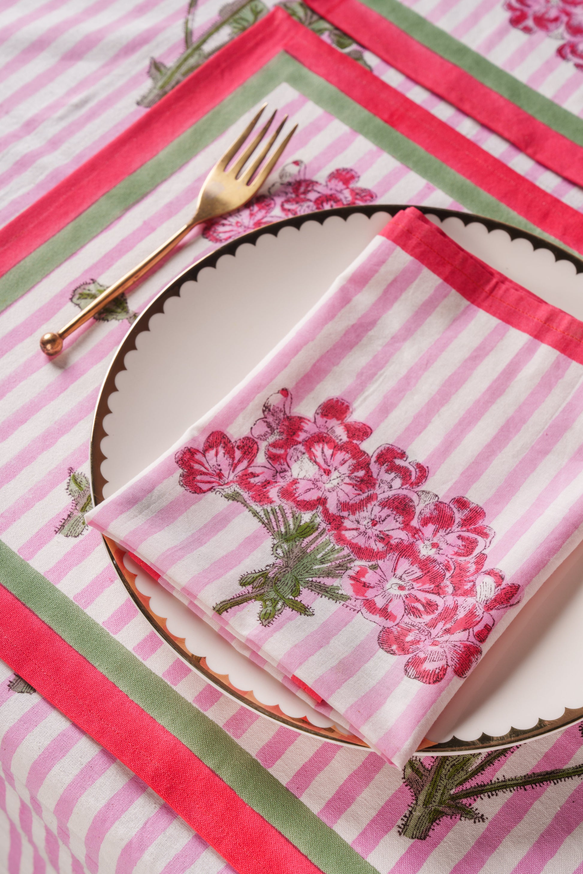 Pink striped blockprint napkin with hydrangea design on scalloped plate