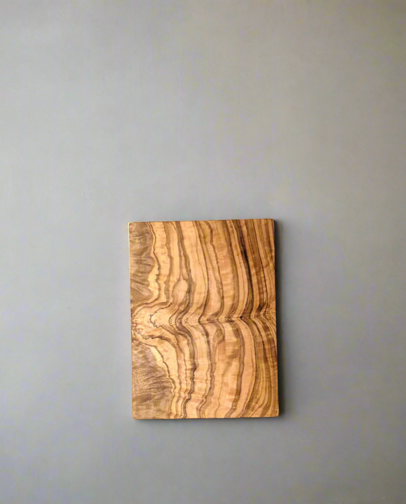 A natural olive wood chopping board displayed on a gray background, highlighting its organic shape, rich wood grain, and smooth, handcrafted finish.