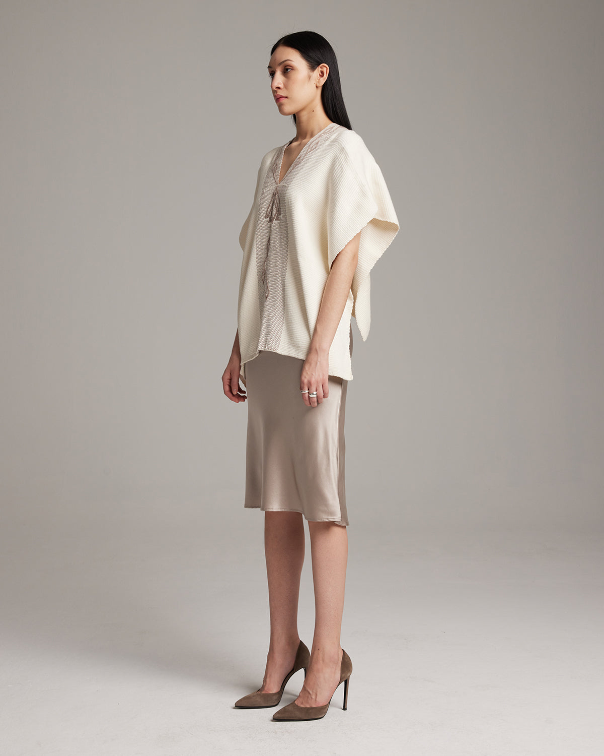 Model wearing a cream Copihue Manta over a satin skirt