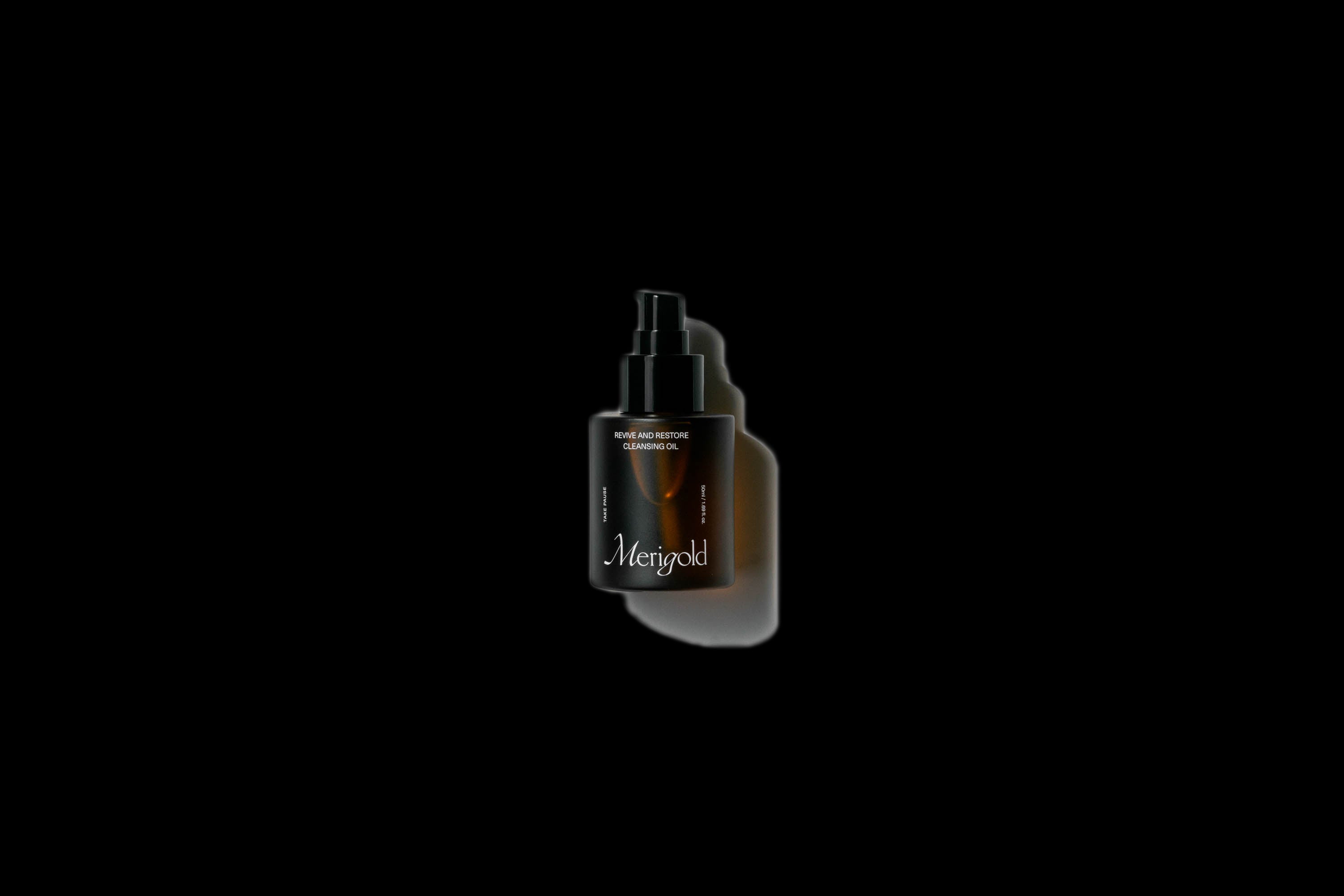 Merigold Revive and Restore Cleansing Oil in amber glass bottle with black pump dispenser isolated on white with shadow