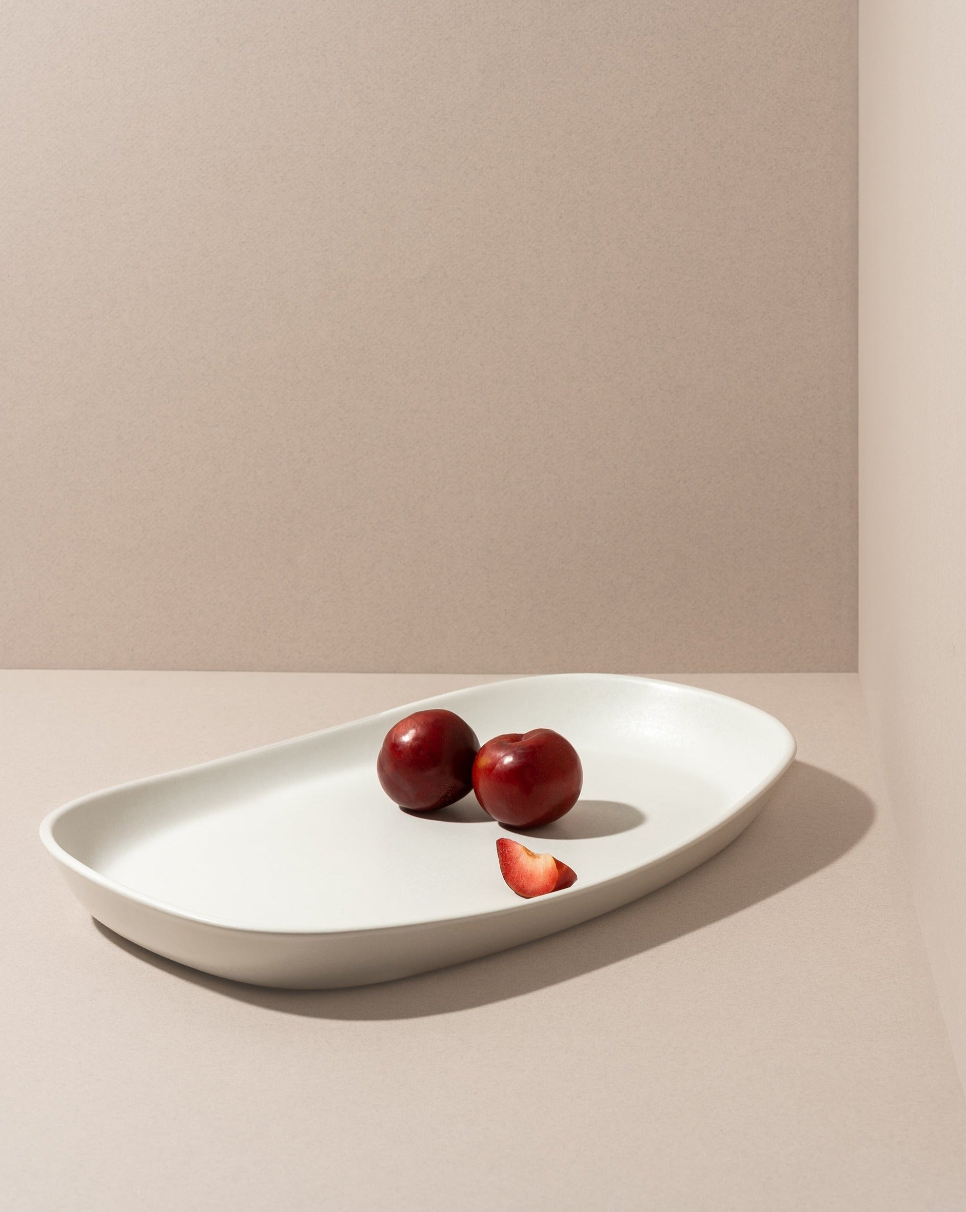 Mini stoneware serving platter with a selection of pastries and blackberries on a kitchen countertop.