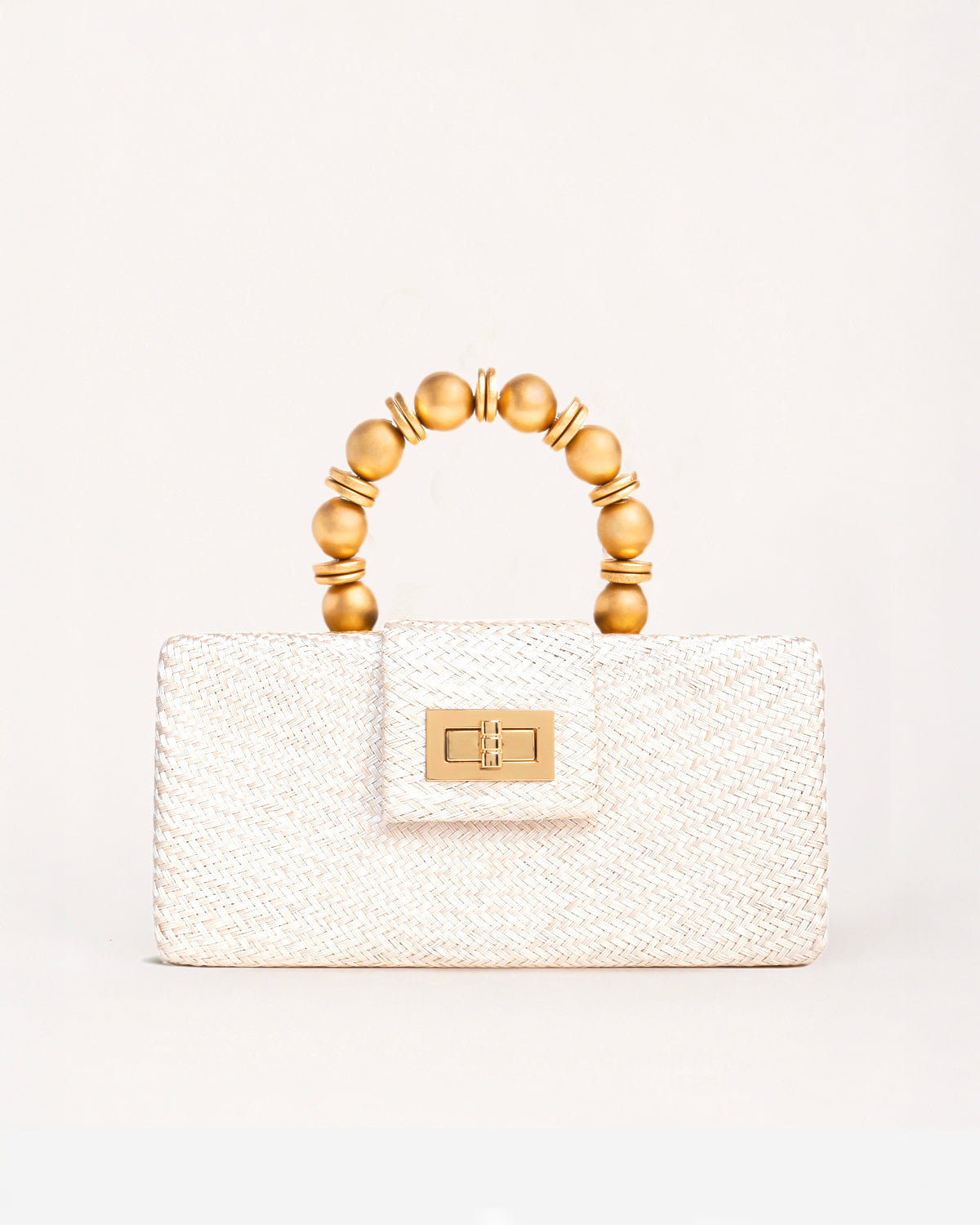 A structured cream-colored woven handbag with a gold-tone clasp and a unique arched top handle made of gold-toned beads, set against a plain off-white background.