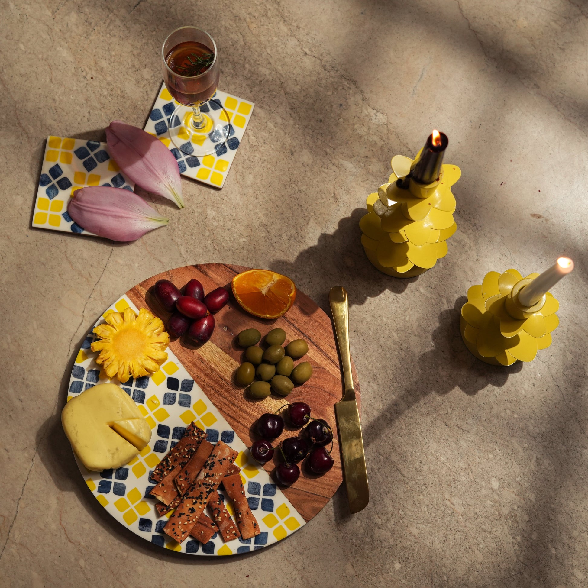 Round acacia wood cheese board with marigold inlay styled with fruit, nuts, and crackers for entertaining.