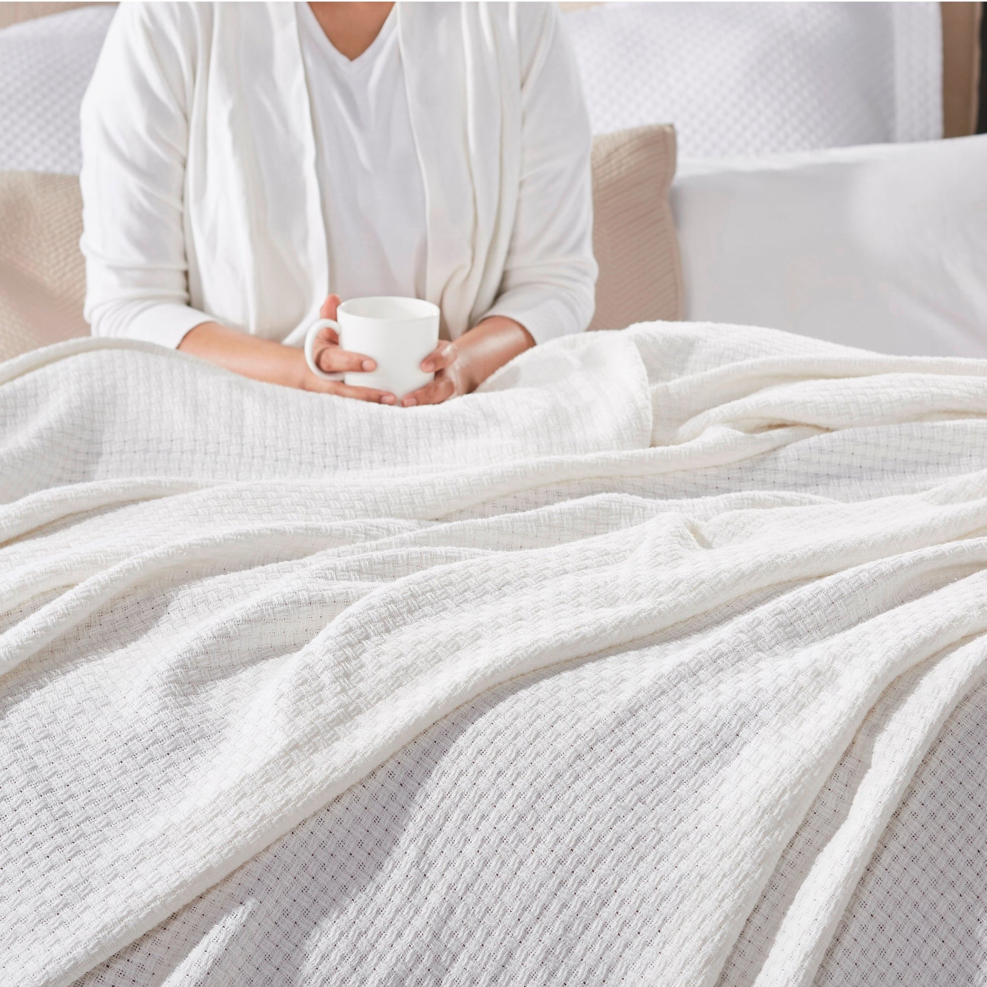 BL-852-11096_2|Person relaxing in bed with a mug, covered by a soft white waffle weave blanket, perfect for cozy morning comfort.