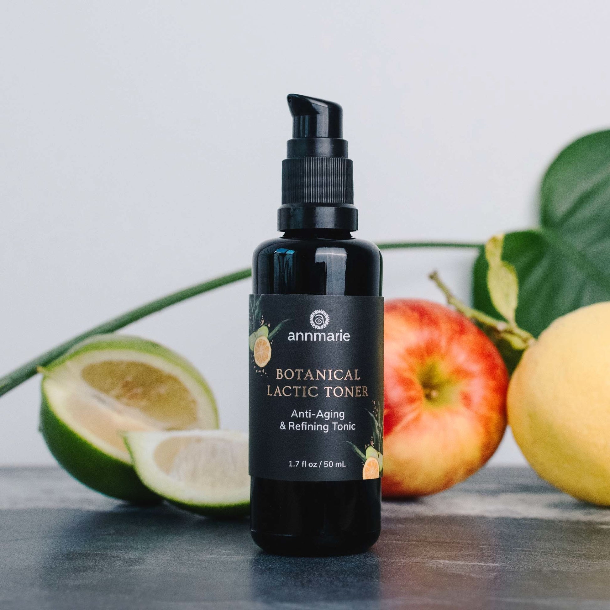 Black bottle of Botanical Lactic Toner with fruits and leaves on a light background