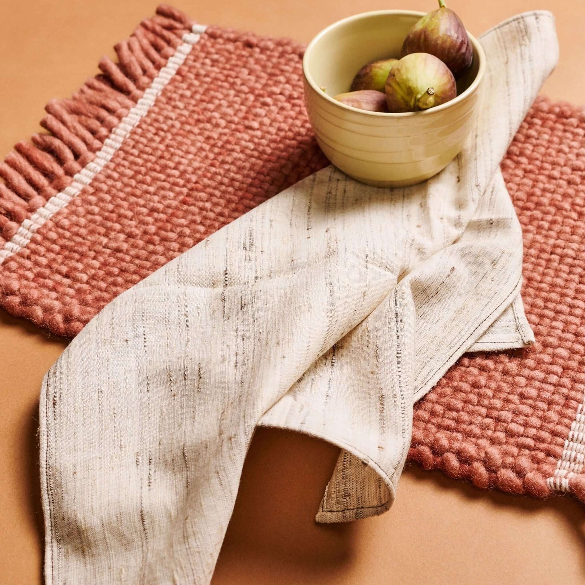 Kora Off White Peace Silk Handloom Napkin set of 4 displayed elegantly with textured mats and a bowl of fruit.