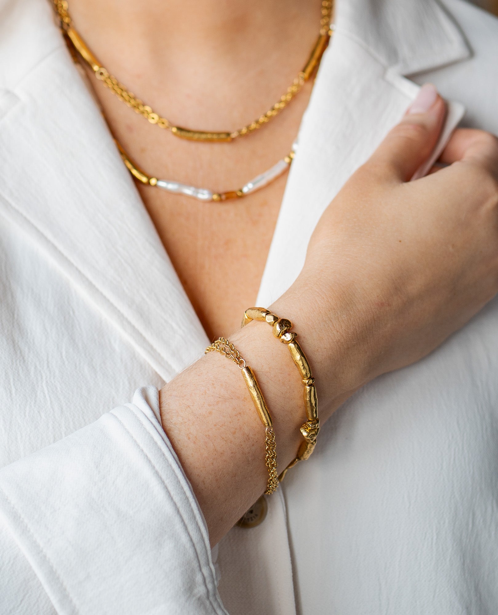 Gold bracelet with a single textured tube bead and double-strand chain.