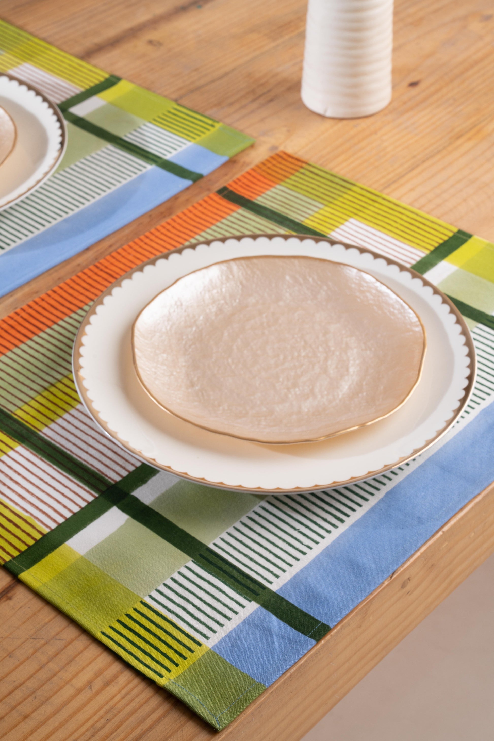 Modernist striped placemats on wooden table with white plates