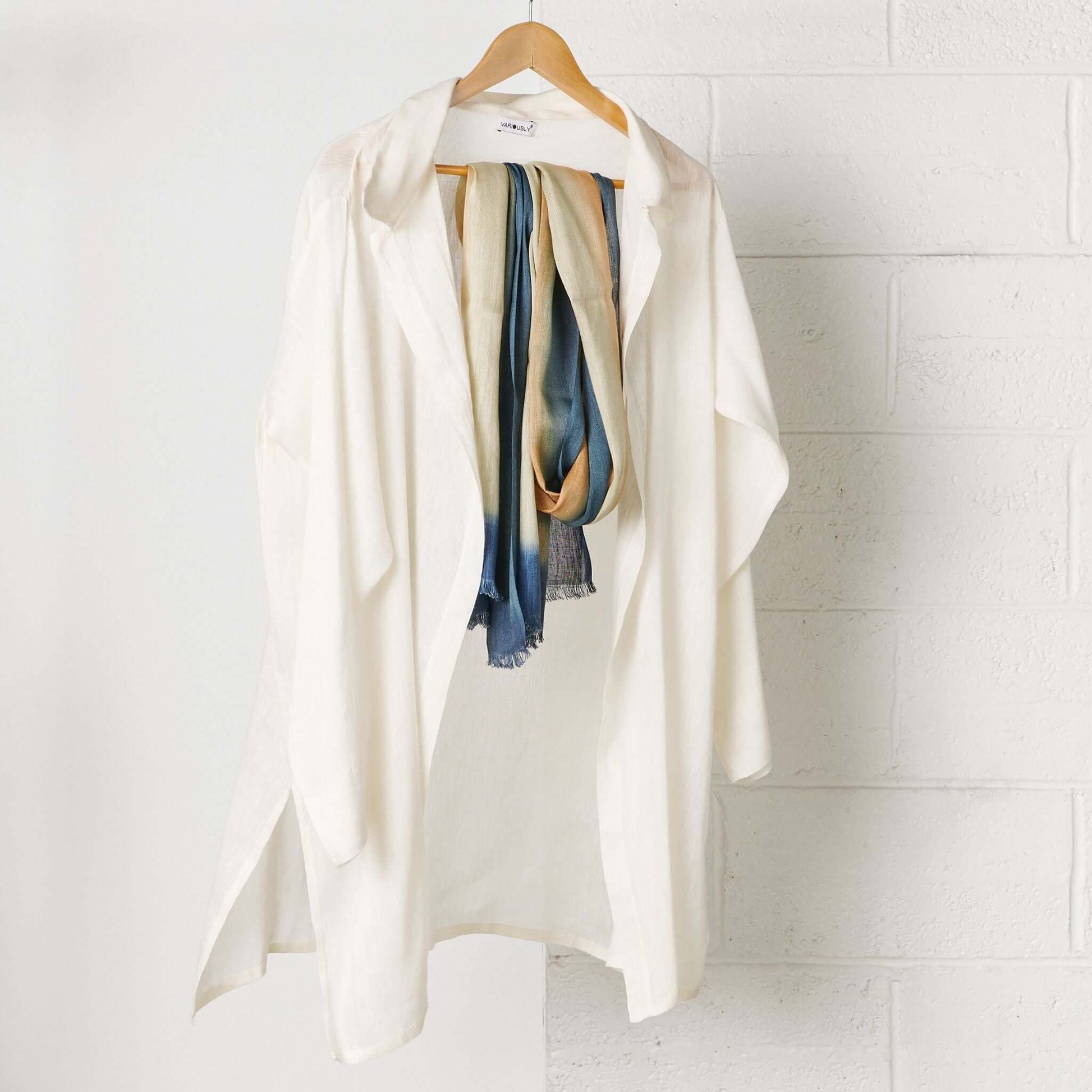 Oceana Beige Soft Linen Silk Handloom Scarf displayed with a white loose-fitting jacket on a wooden hanger.
