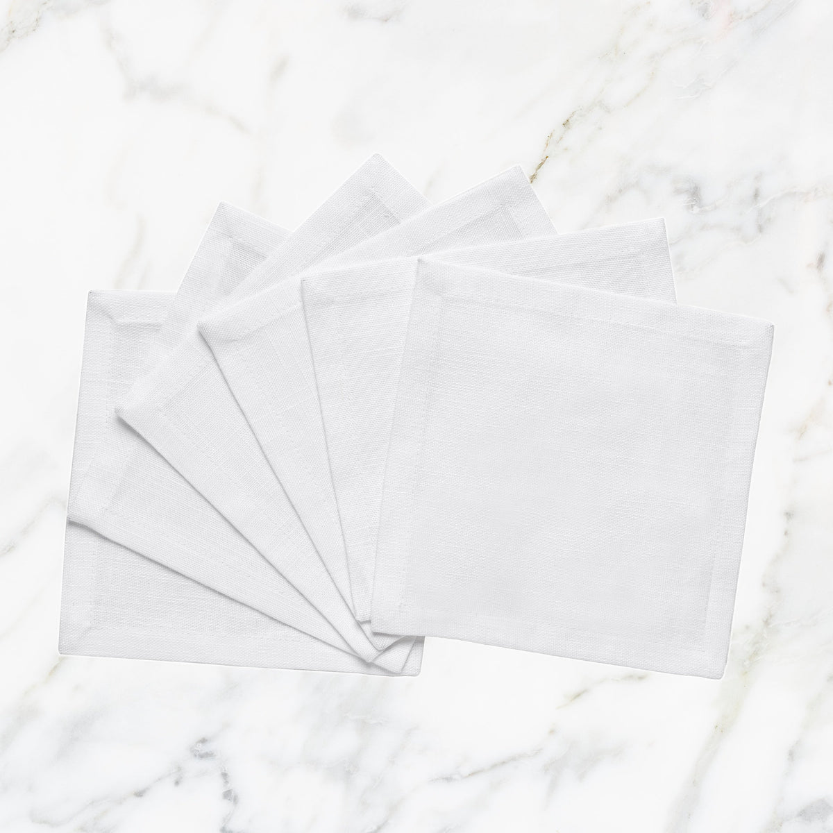 CNP-4909-66_1|Set of fanned white linen napkins displayed on a pristine white marble background for elegant table settings.