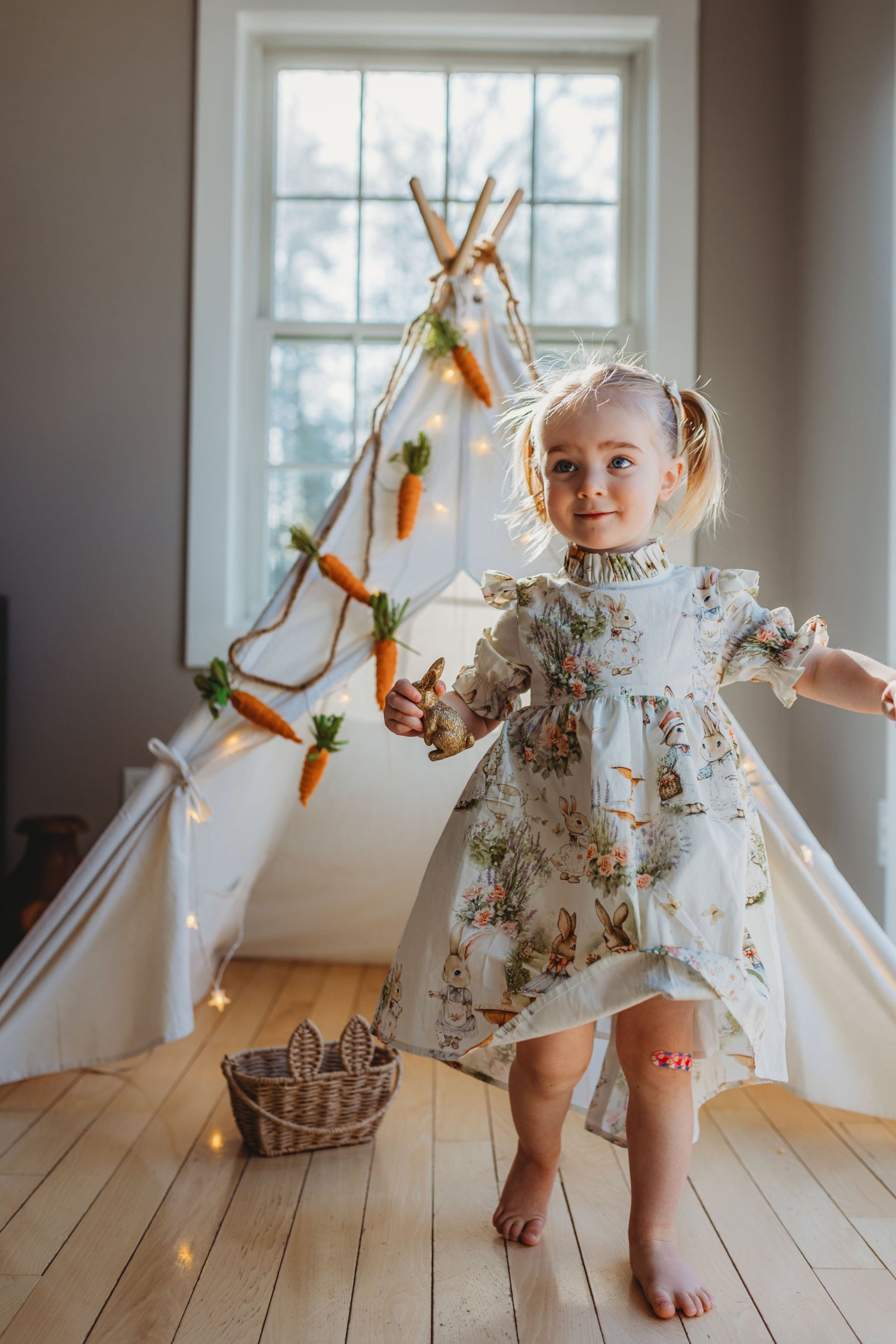 Young girl in a floral dress standing in a room with a decorative carrot and carrot top Christmas tree.