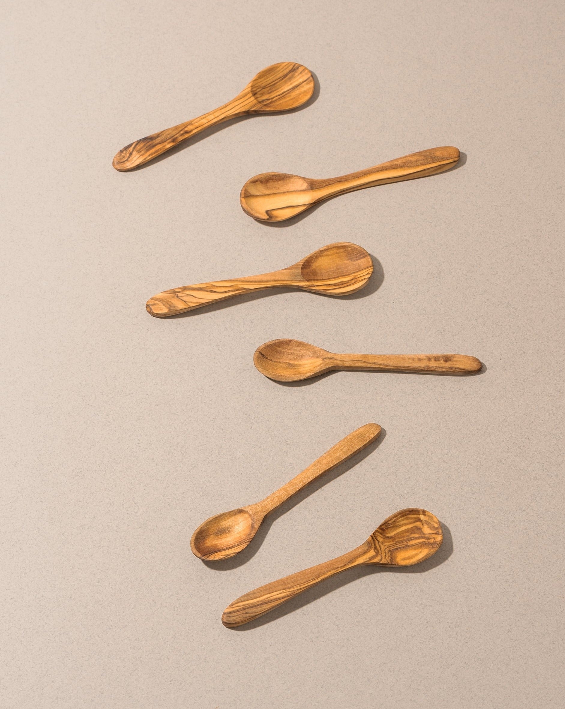 A collection of wooden coffee spoons laid out on a surface, displaying a natural wood finish and ergonomic shapes.