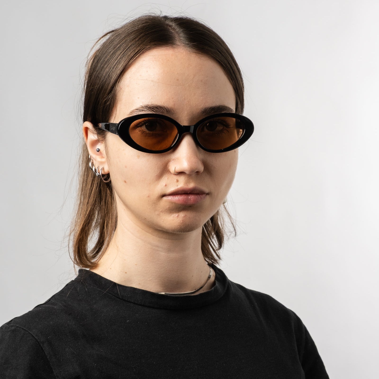 Female wearing Sad Eyewear Bloom oval sunglasses in black with tinted bronze lenses