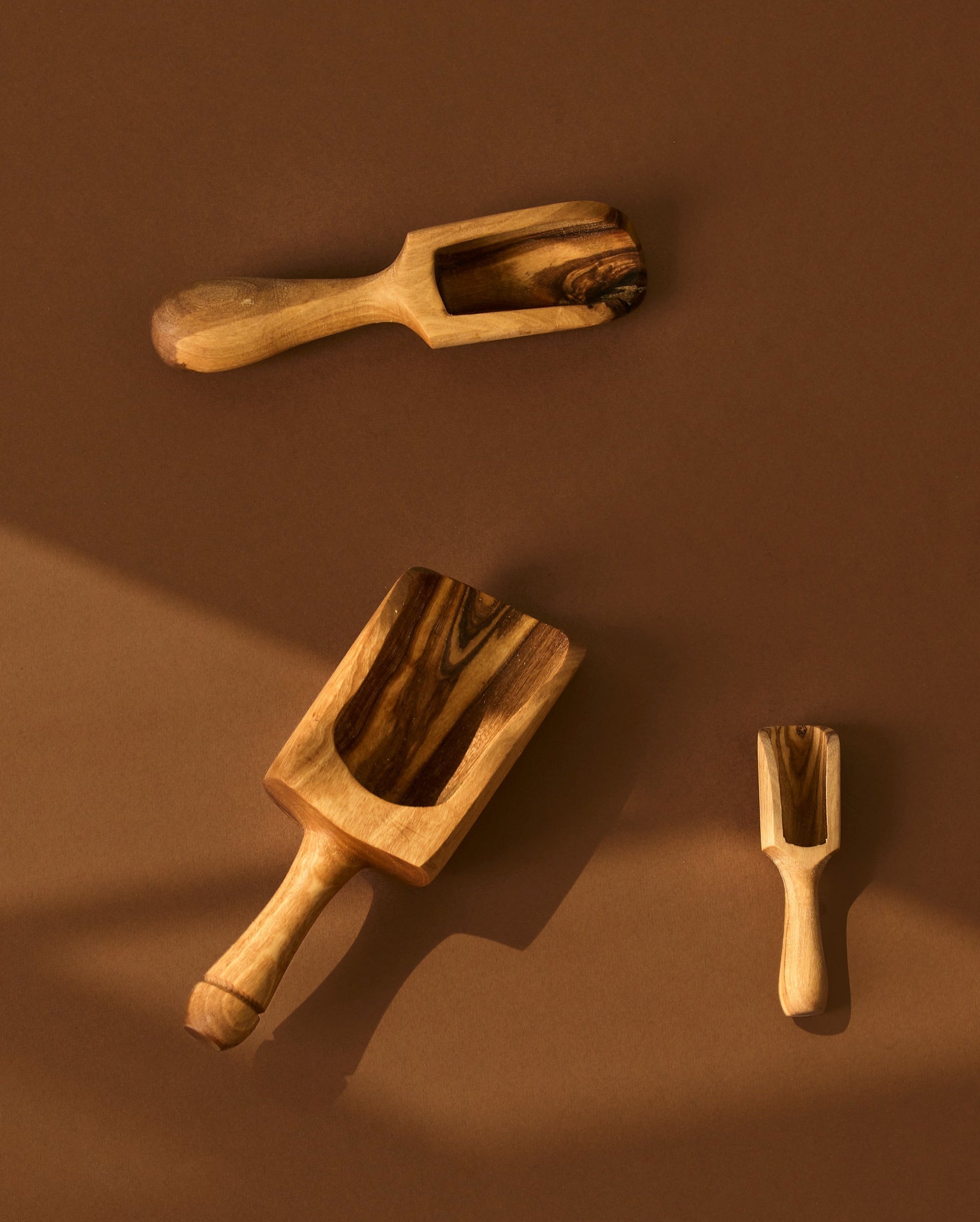 A collection of wooden scoops of various sizes, displayed against a brown background.