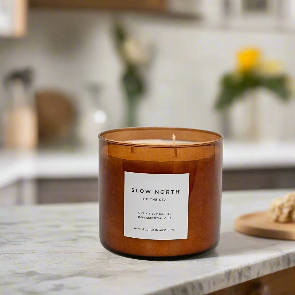 Natural Coastal Candle by Slow North sitting on a counter in a pretty kitchen