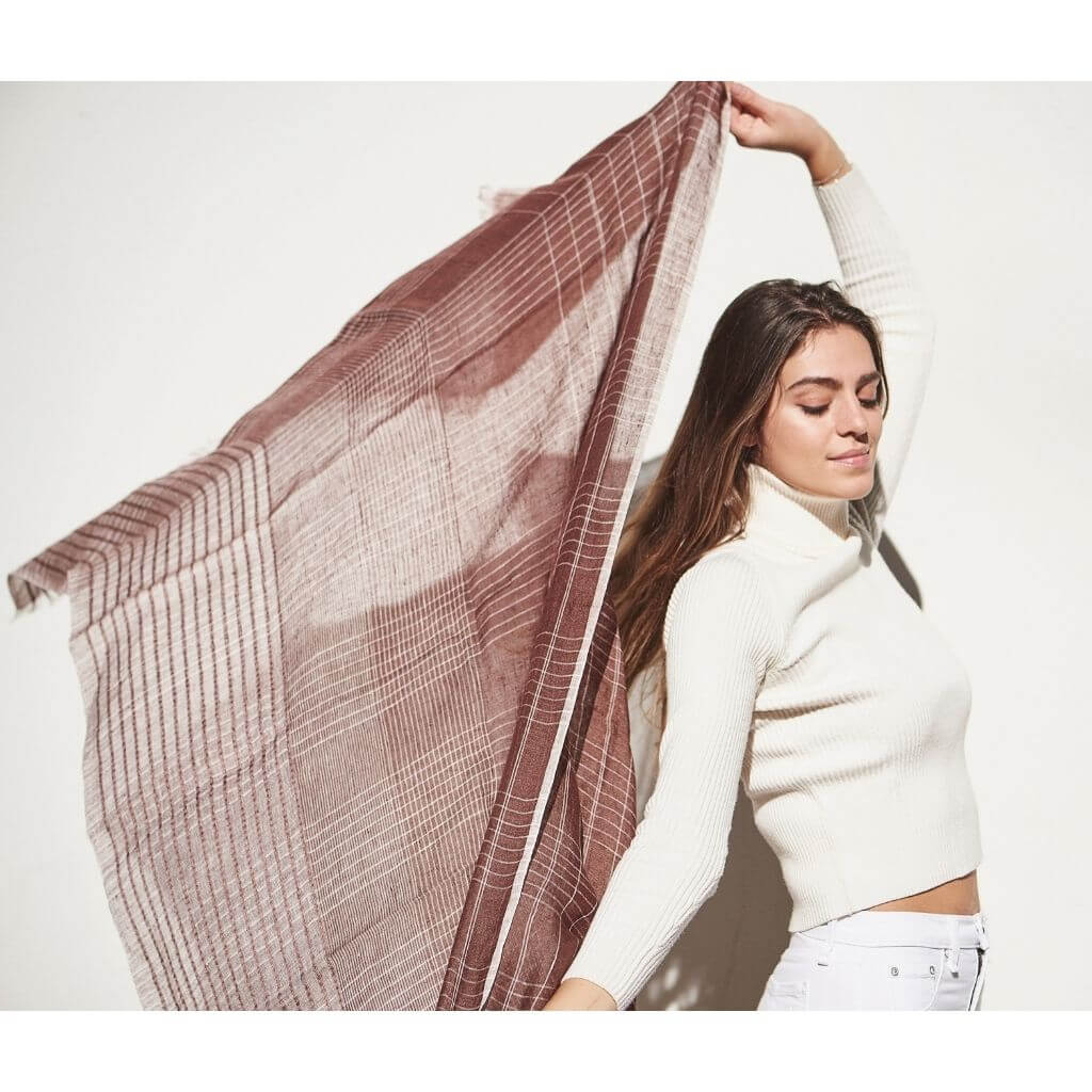 Woman wearing Auro Cinnabar Handwoven Earthy Rust Maroon Linen Scarf, showcasing its unique texture and pattern.