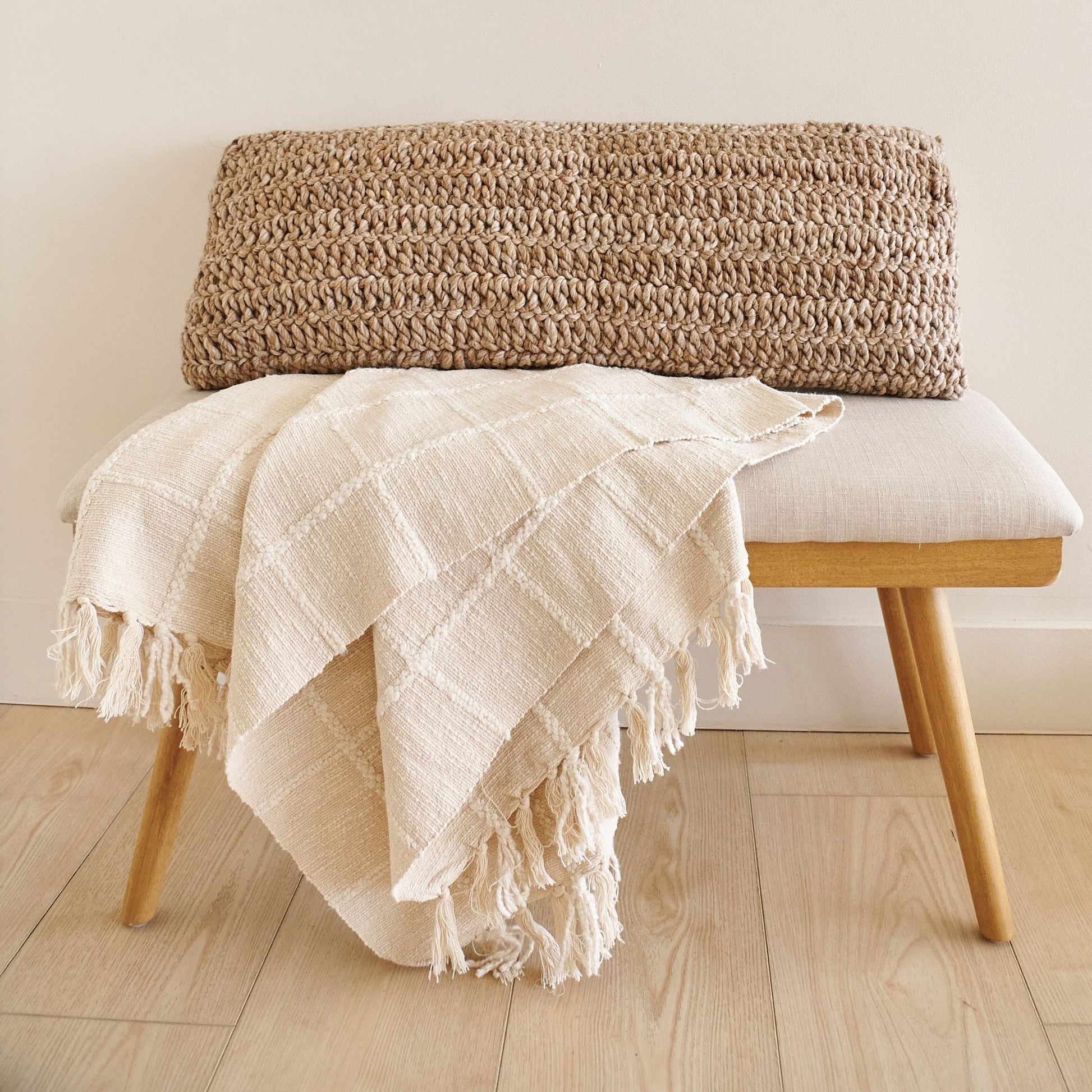 Sea Shell White Textured Checks Handloom Throw draped over a bench, showcasing its elegant texture and hand-rolled fringes.