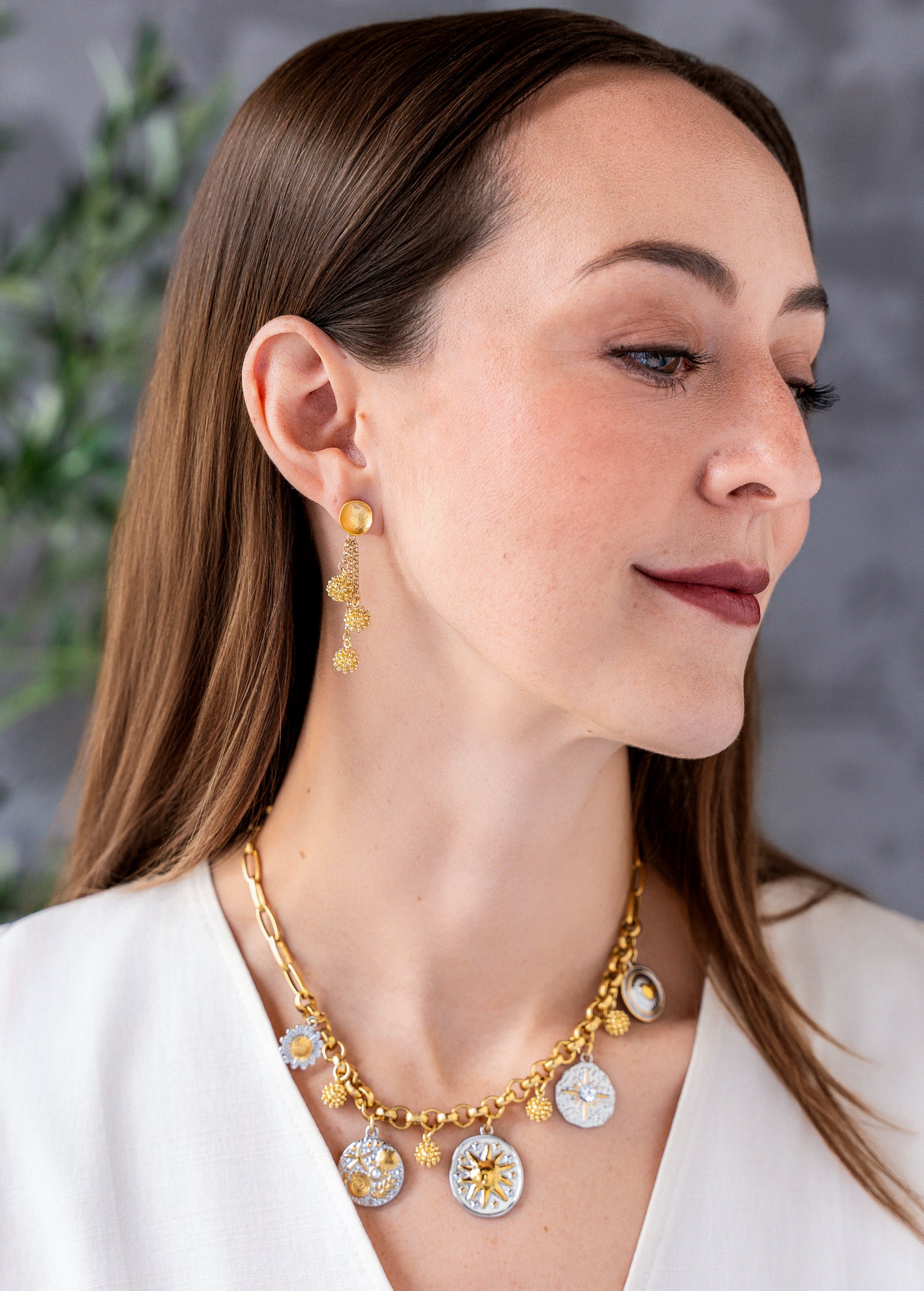 Mixed metal charm necklace with celestial, floral, heart, and ocean inspired charms hanging from a gold chain necklace.