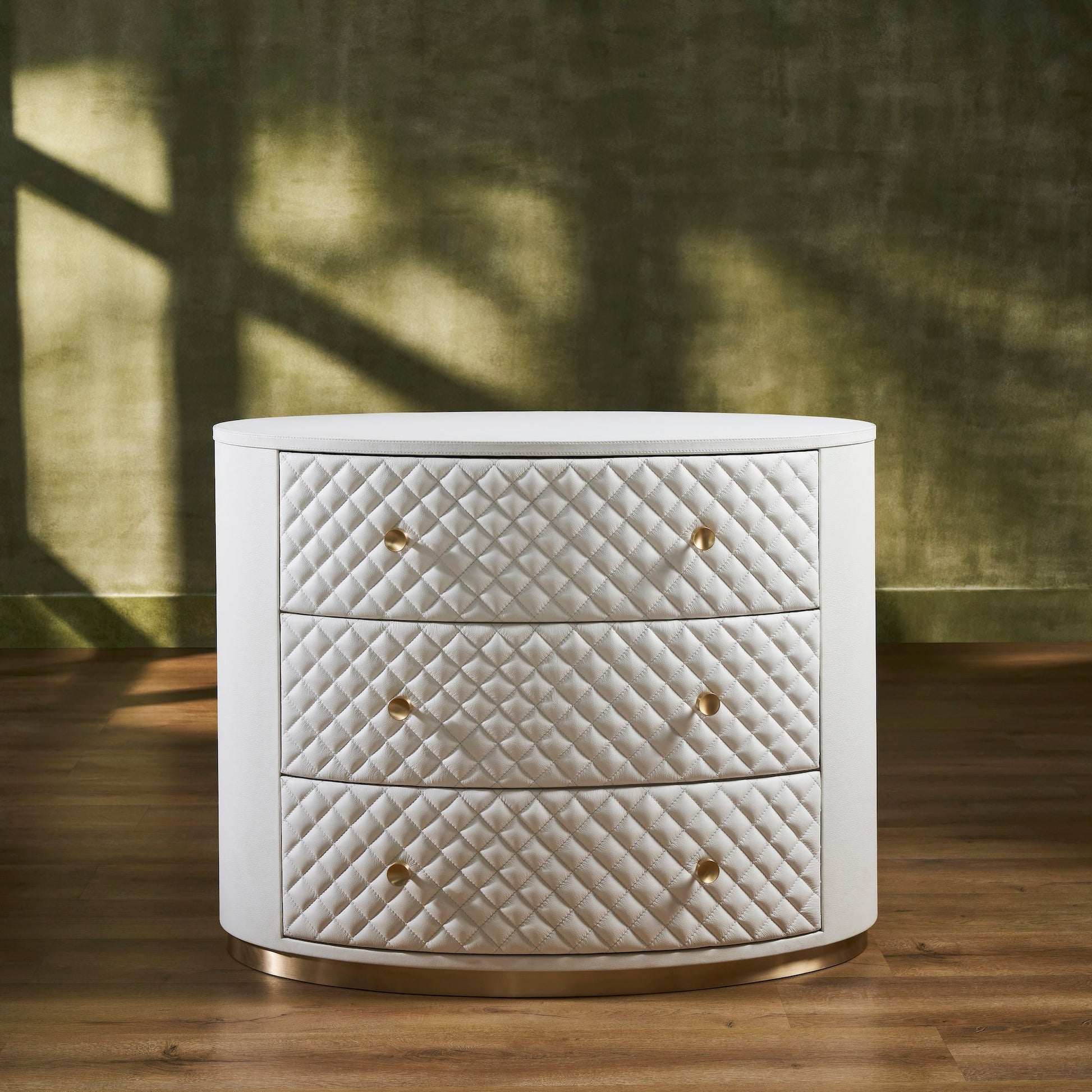 FN-5218-482036_1|Elegant white leather oval chest of drawers, featuring a chic quilted design, radiant gold hardware, and a sleek gold base.