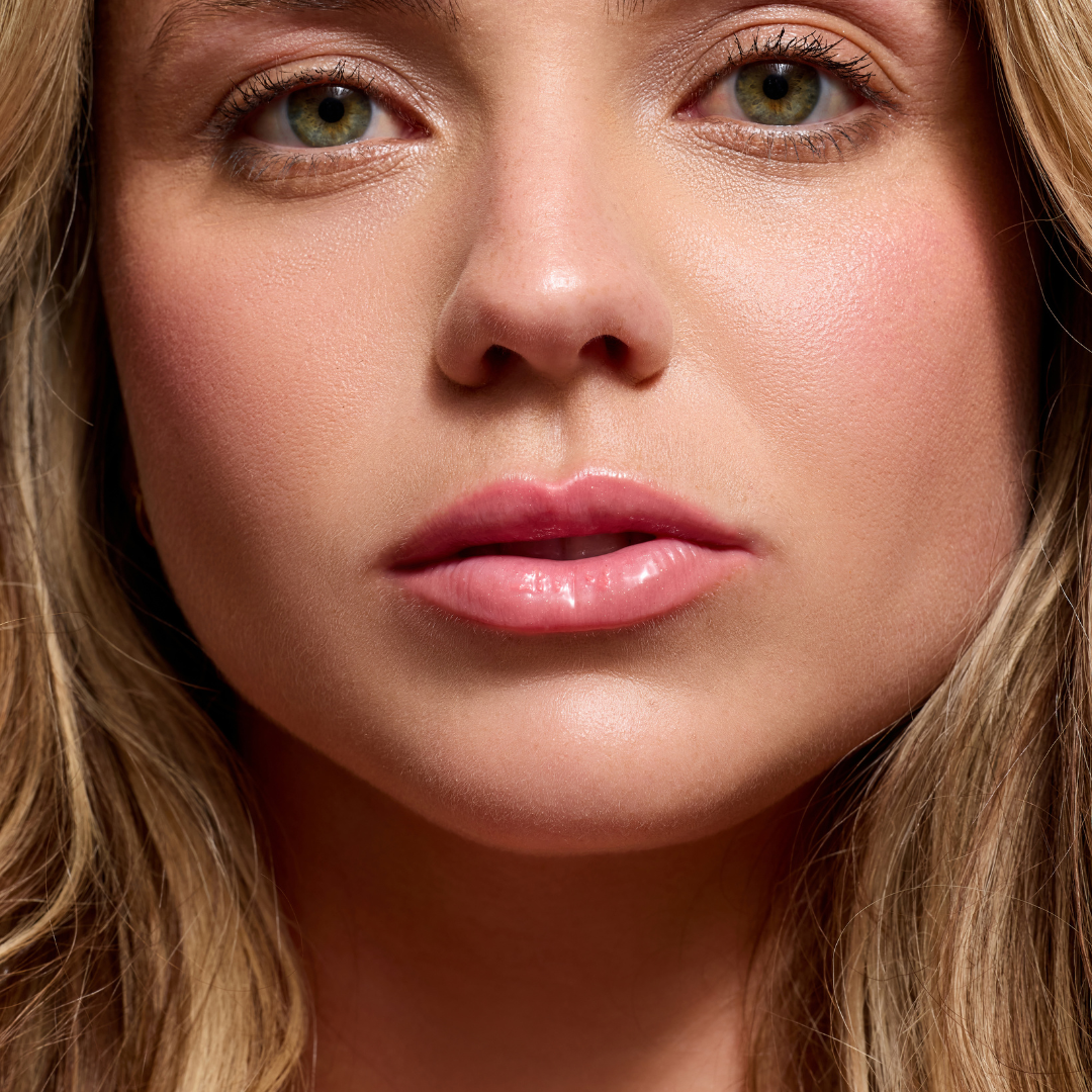 Woman wearing Côte Beauty The Necessity Peptide Lip Shine Branson Coral Non-Toxic Lip Gloss on her lips. 