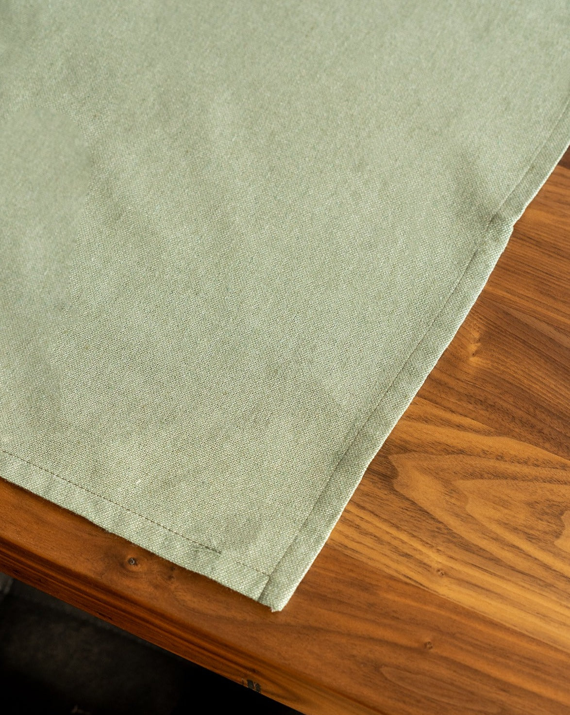 A green cotton placemat is laid out on a wooden table.