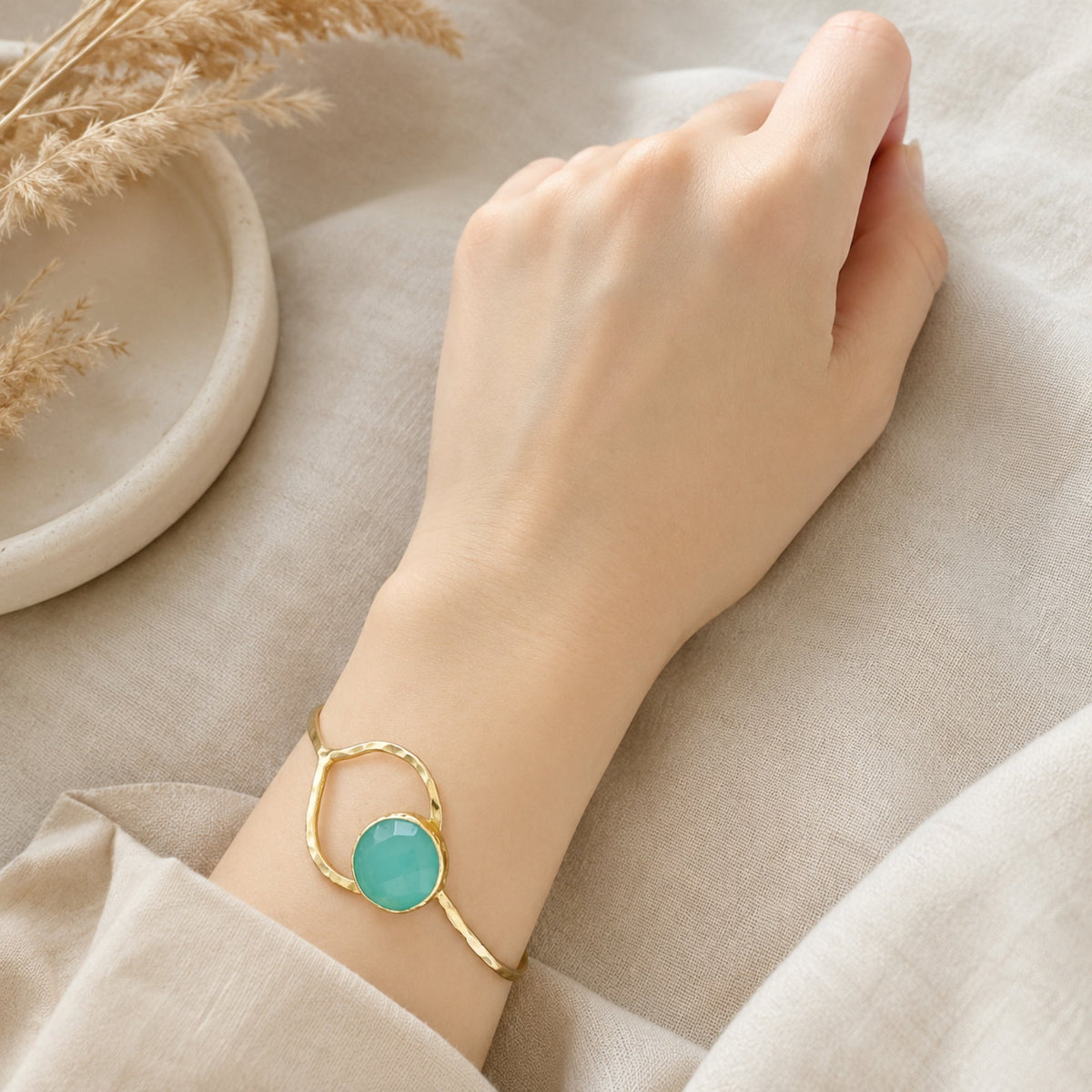 Gold-plated Aqua chalcedony bracelet on a wrist against a neutral background