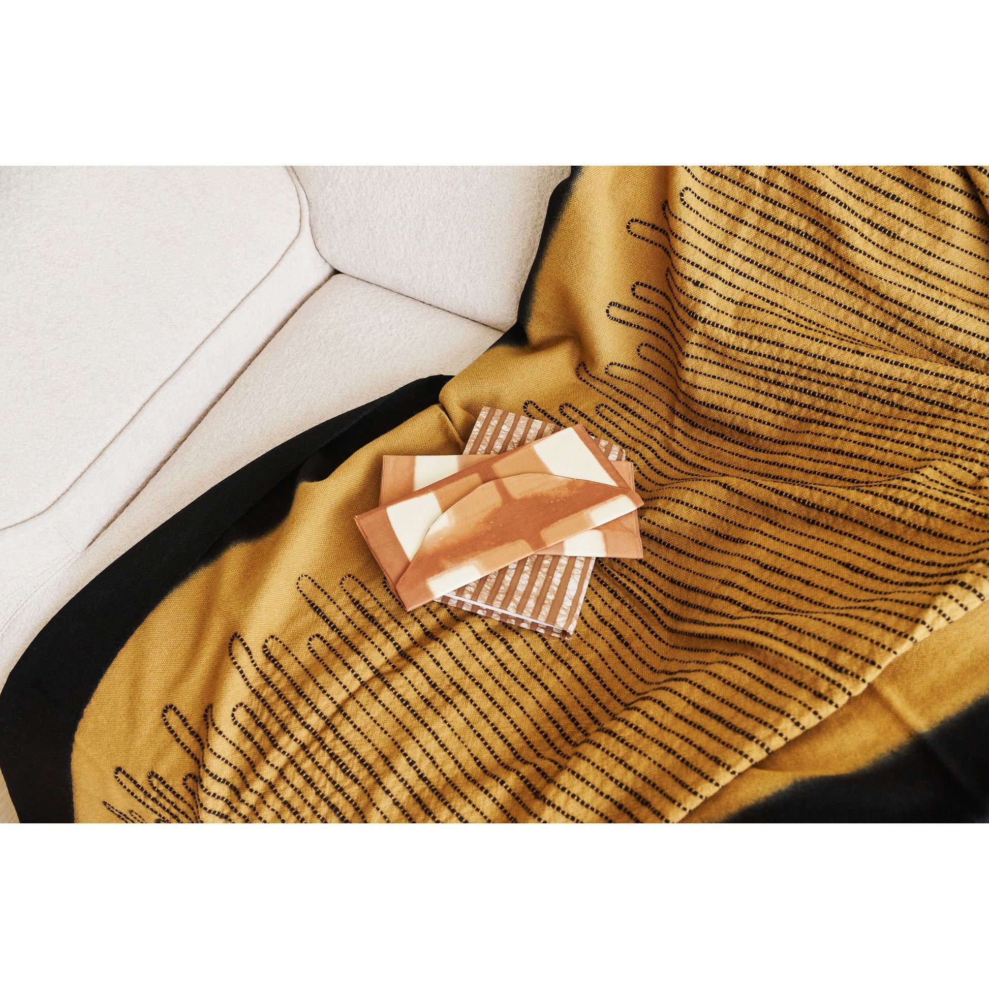Handwoven Topaz Brown Myrtle Drift Merino Throw draped on a sofa with decorative items on top.