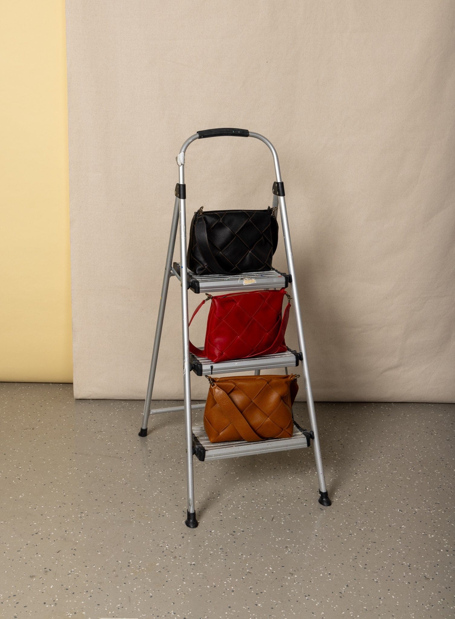 Step ladder with three bags on a plain background